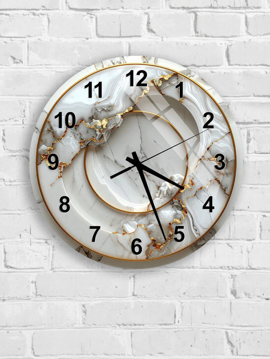 A white marble wall clock with gold accents and black numbers is mounted on a white brick wall.