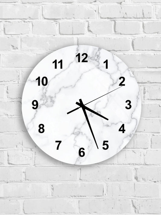 A white marble wall clock with black numbers and hands is mounted on a white brick wall.