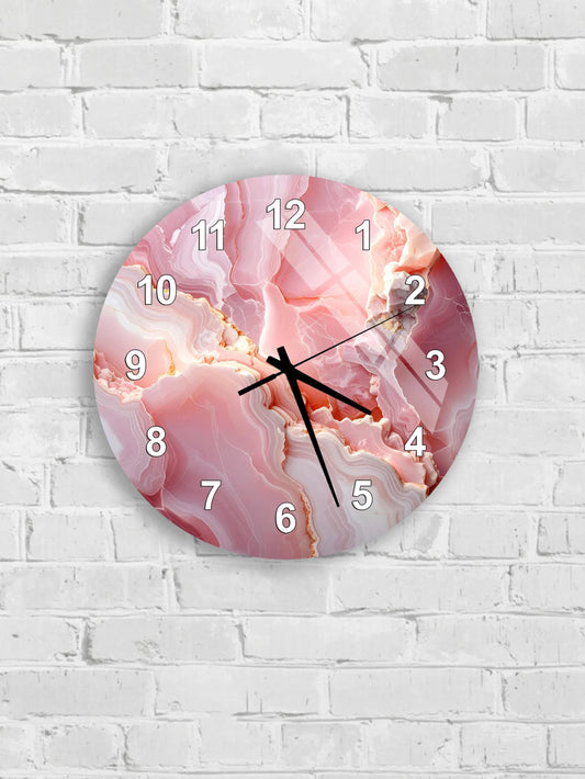 A round wall clock with a pink marble-like design on its face, mounted on a white brick wall.
