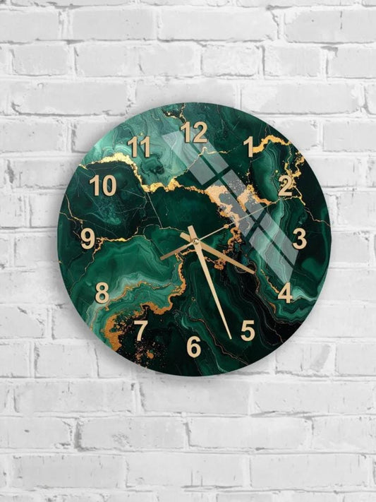 A wall clock with a green marble-like design and gold numbers is mounted on a white brick wall.