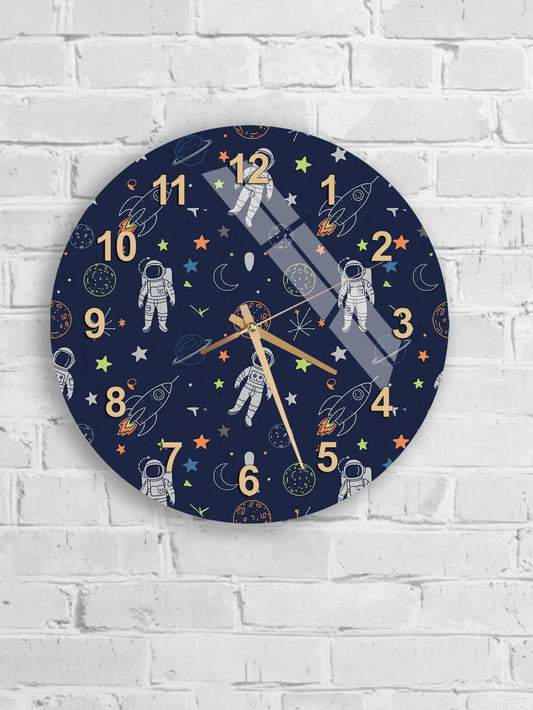 A wall clock with a space-themed design, featuring astronaut silhouettes and celestial objects such as planets, stars, and comets.