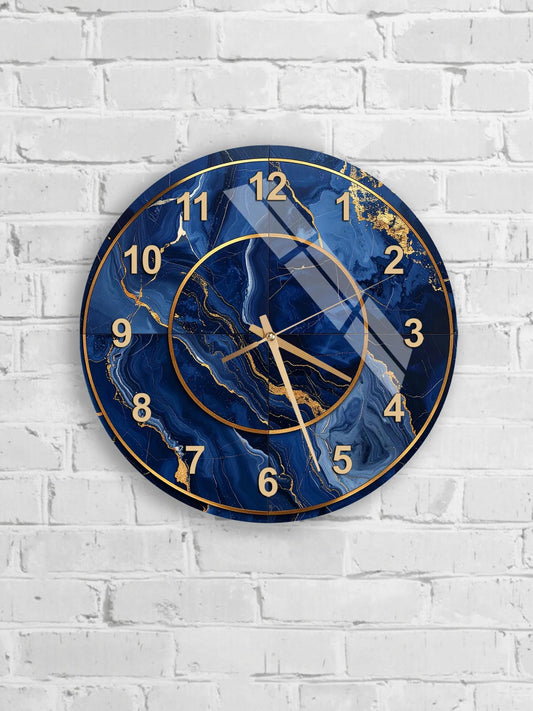 A wall clock with a marble-like blue and gold design, mounted on a white brick wall.