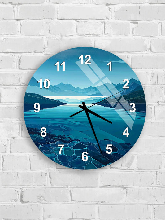 A wall clock with a serene landscape of mountains, water, and a lake on its face, mounted on a white brick wall.