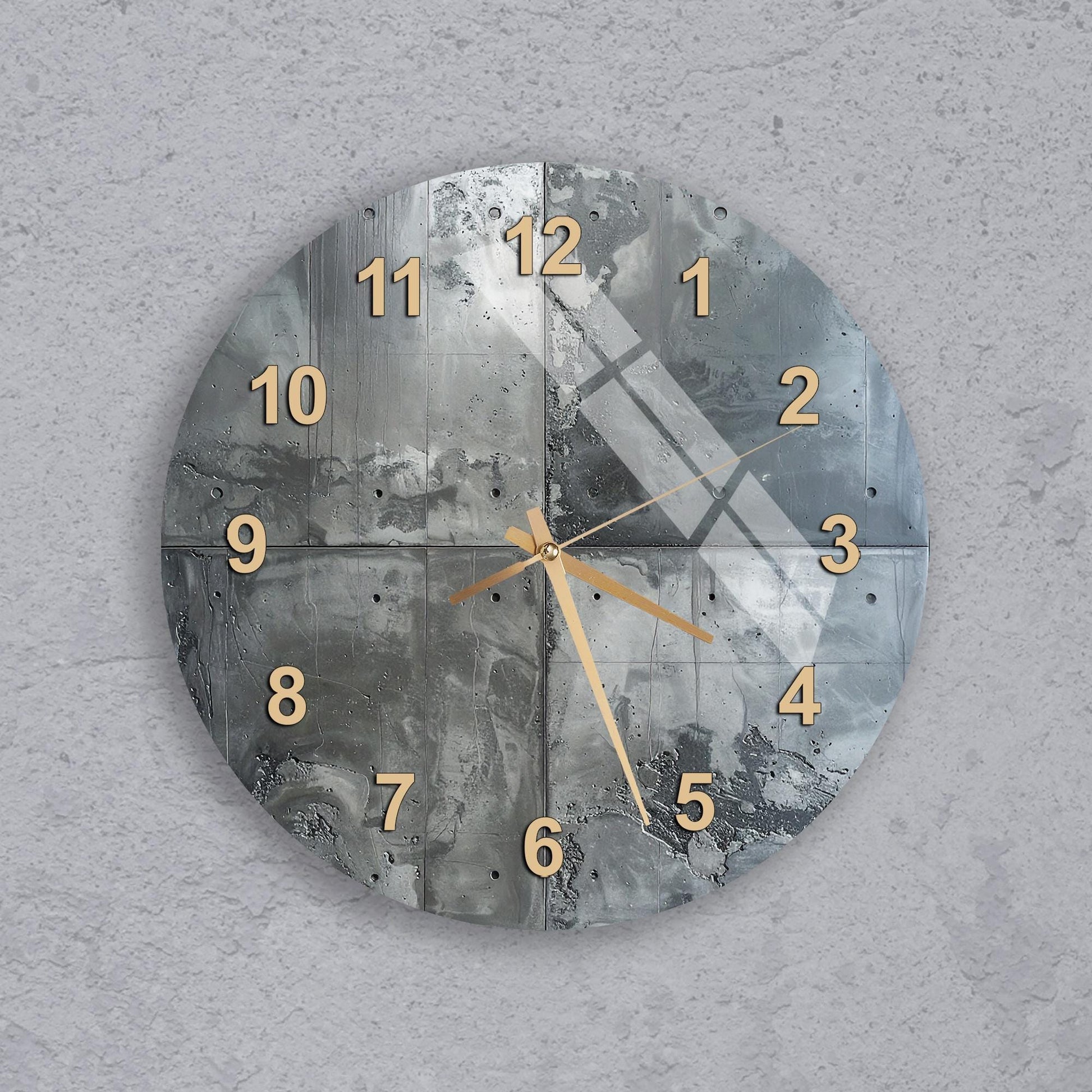 A wall clock with a metallic, textured design and gold numbers on a gray background.