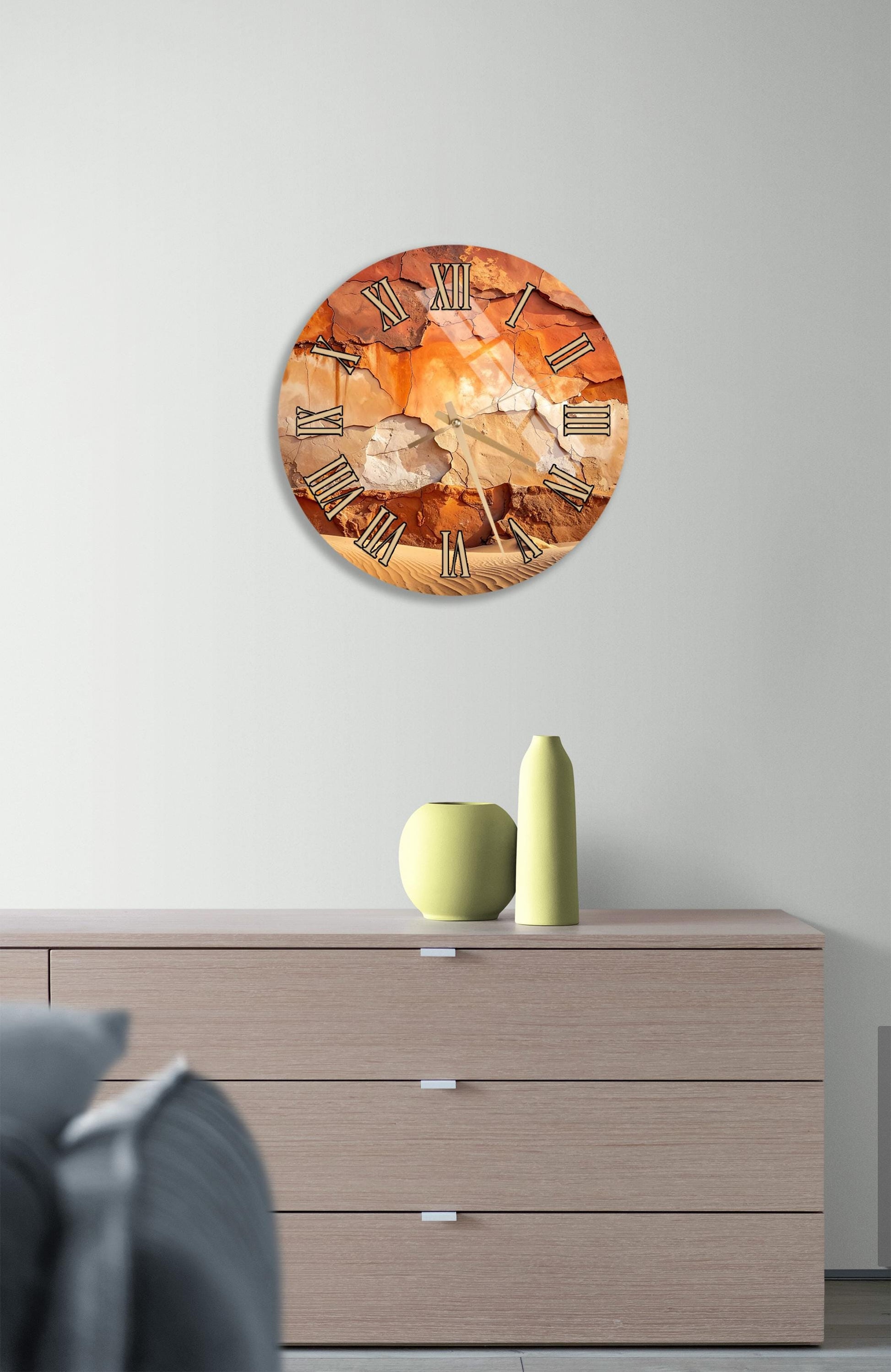 a wall clock with a rustic design, mounted on a wall above a wooden dresser. The dresser has three drawers and contains a yellow vase and a green vase.