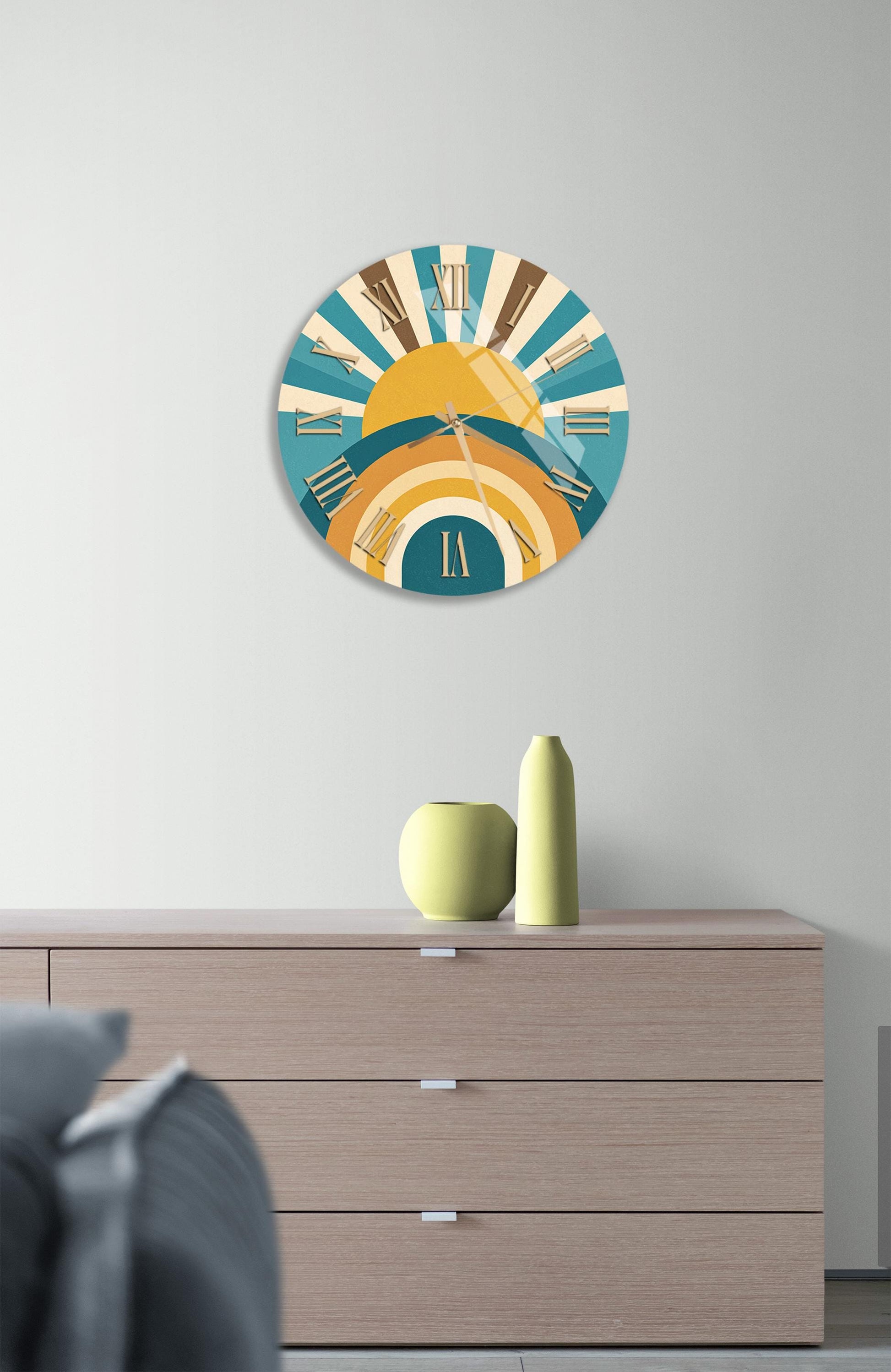 a wall clock with a colorful design, mounted on a wall above a wooden dresser with three drawers.