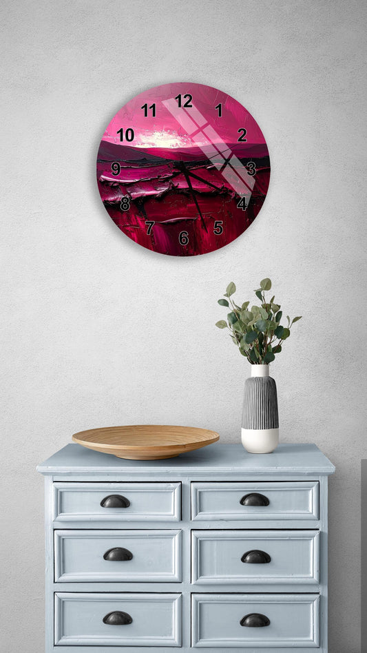 a wall clock with a pink and purple design, mounted on a wall above a wooden dresser with drawers. The dresser also has a vase with greenery and a wooden bowl on it.
