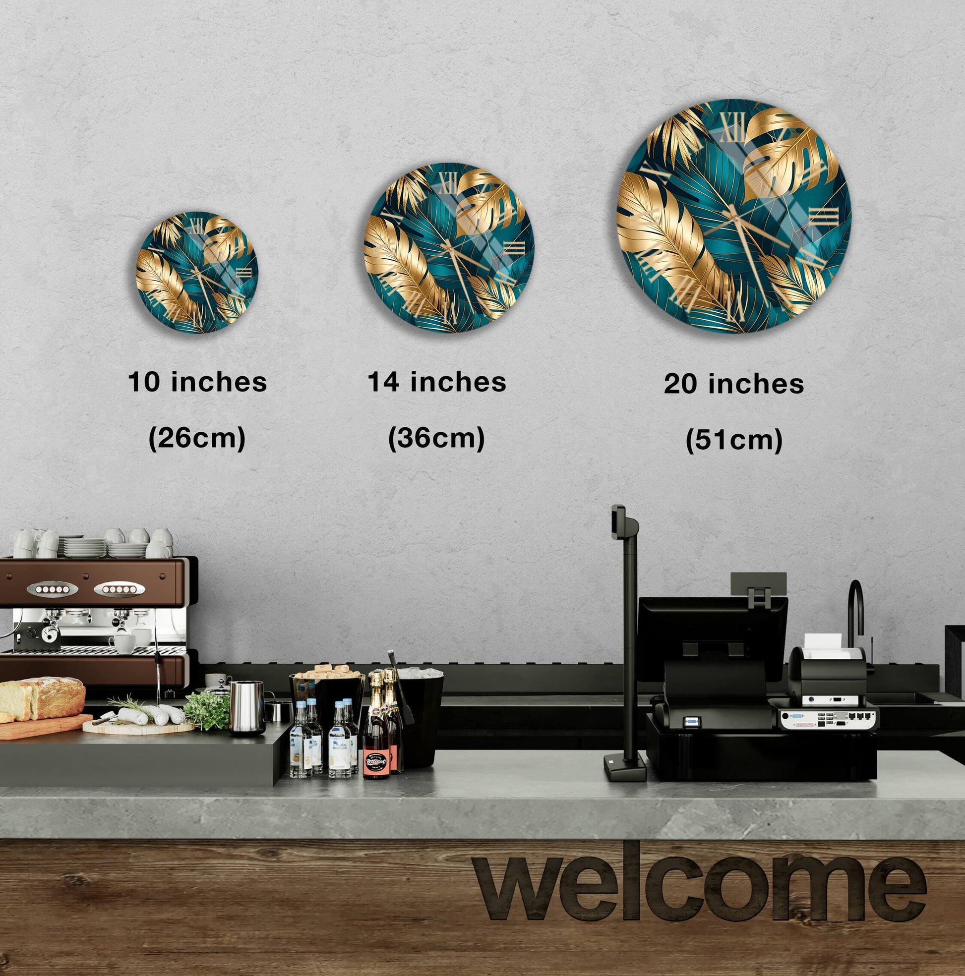 A wall clock with a tropical leaf design is displayed on a wall, accompanied by three different sizes of the same clock. Below the clock, there is a counter with various items, including bottles and a sandwich. The word "welcome" is written on the counter.