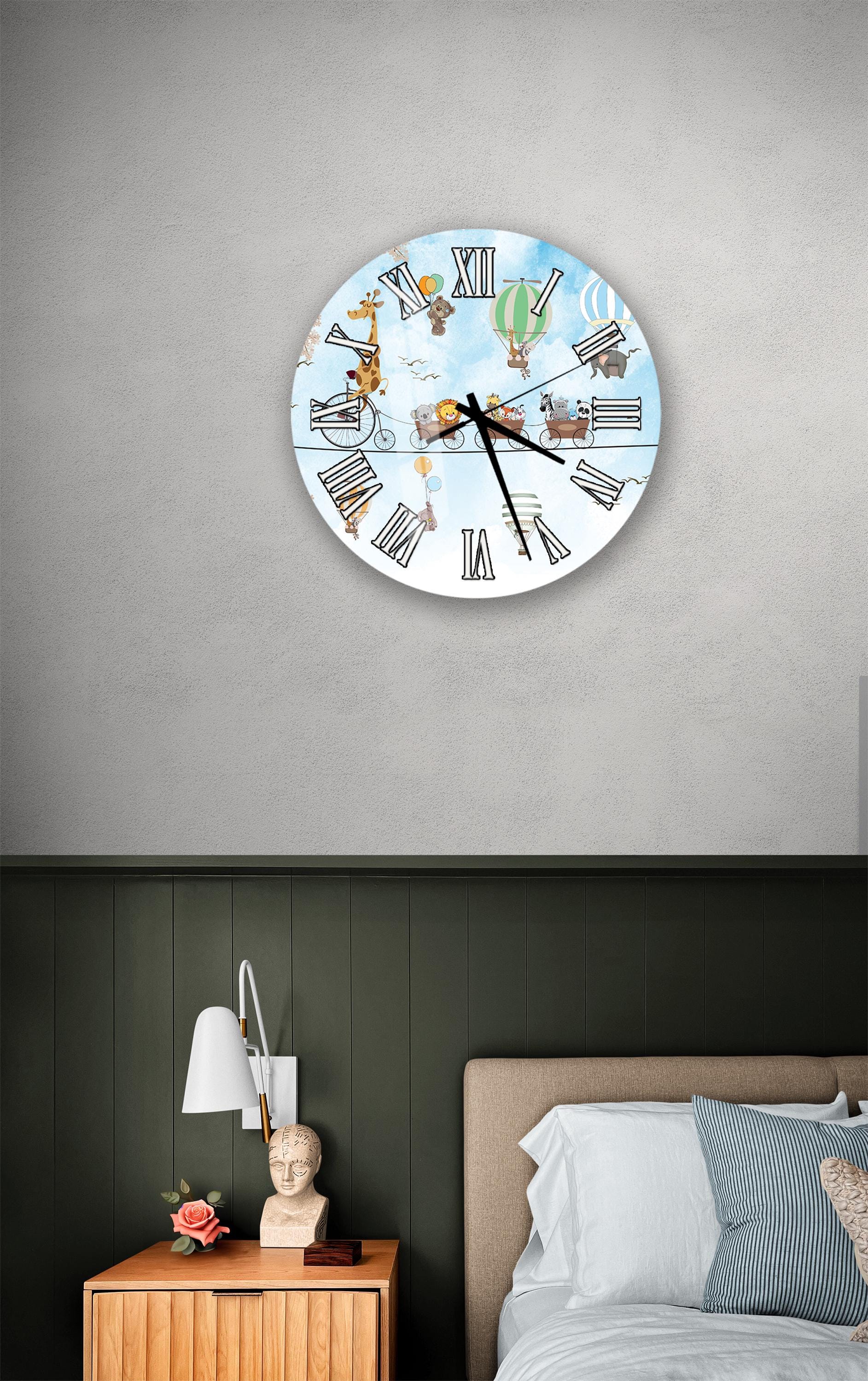 a clock with a giraffe and hot air balloons on its face, mounted on a wall above a bedside table with a lamp and a small statue.