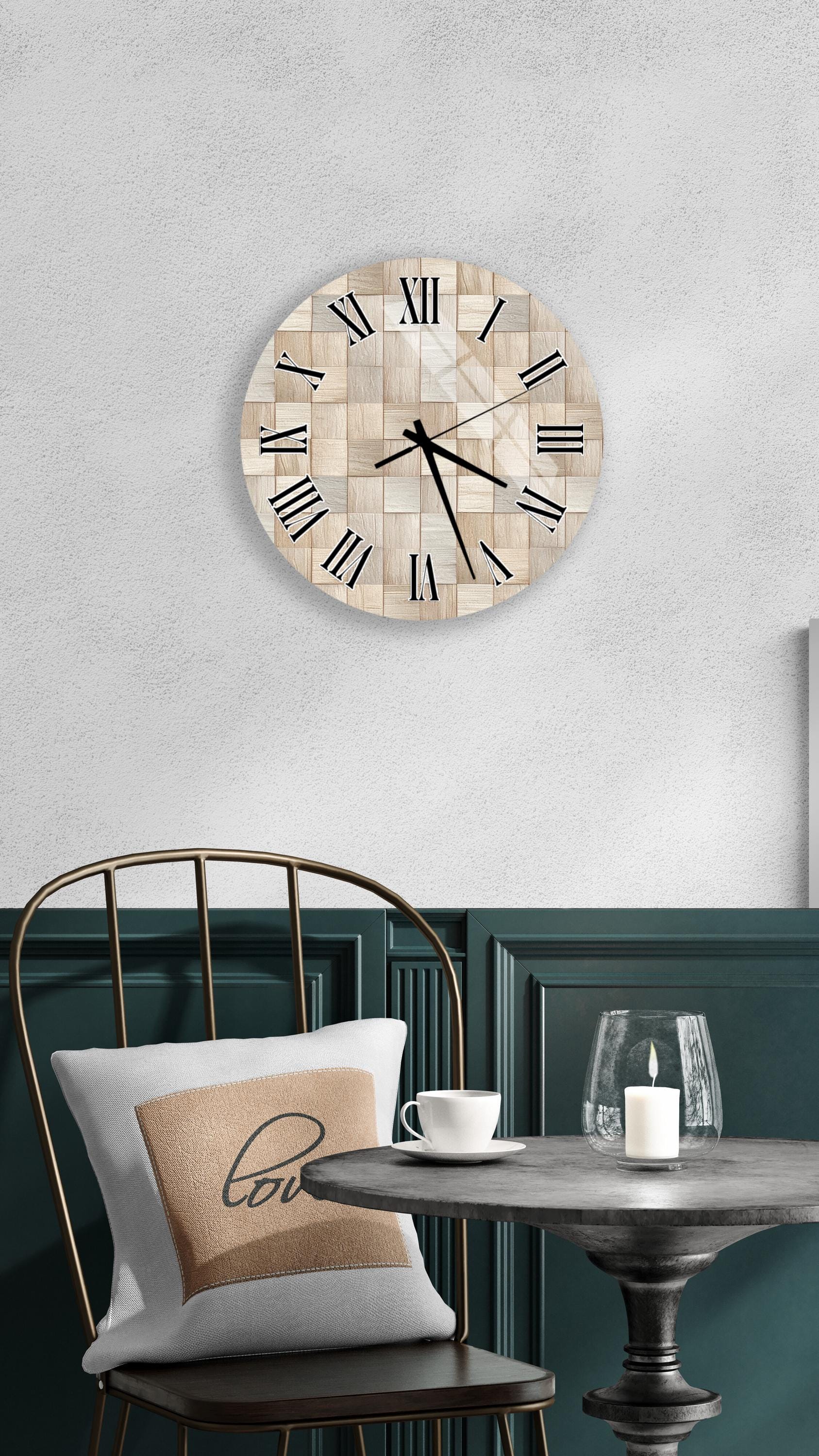 a modern interior design with a round wooden clock mounted on a wall above a table with a white tablecloth. The table has a glass candle holder and a white coffee cup on it. A white pillow with the word "love" printed on it is placed on the chair.