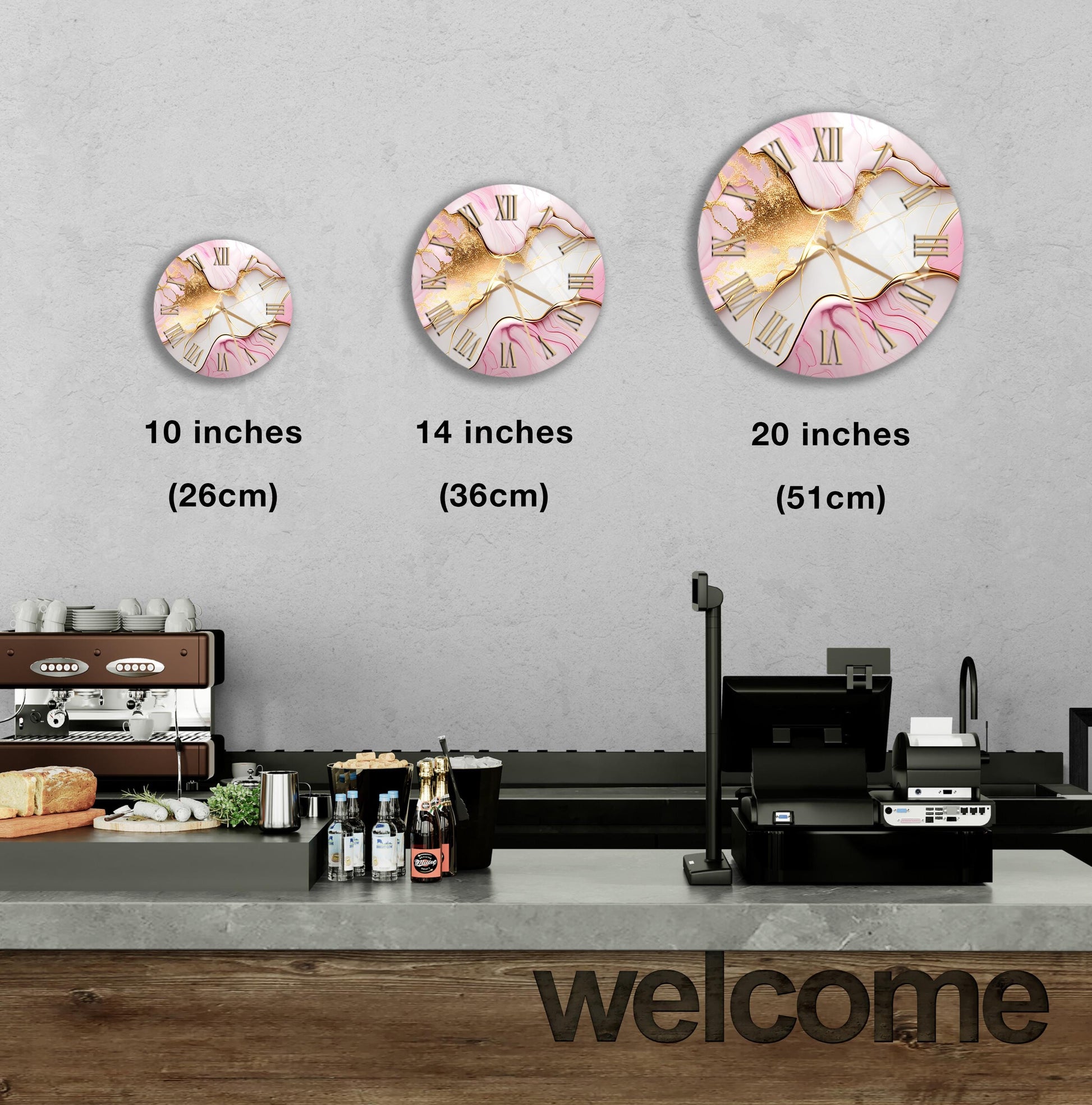 a wall with three different sizes of pink and gold wall clocks, each with Roman numerals. Below the clocks, there is a counter with various items such as bottles and a sandwich. The word "welcome" is also visible in the image.