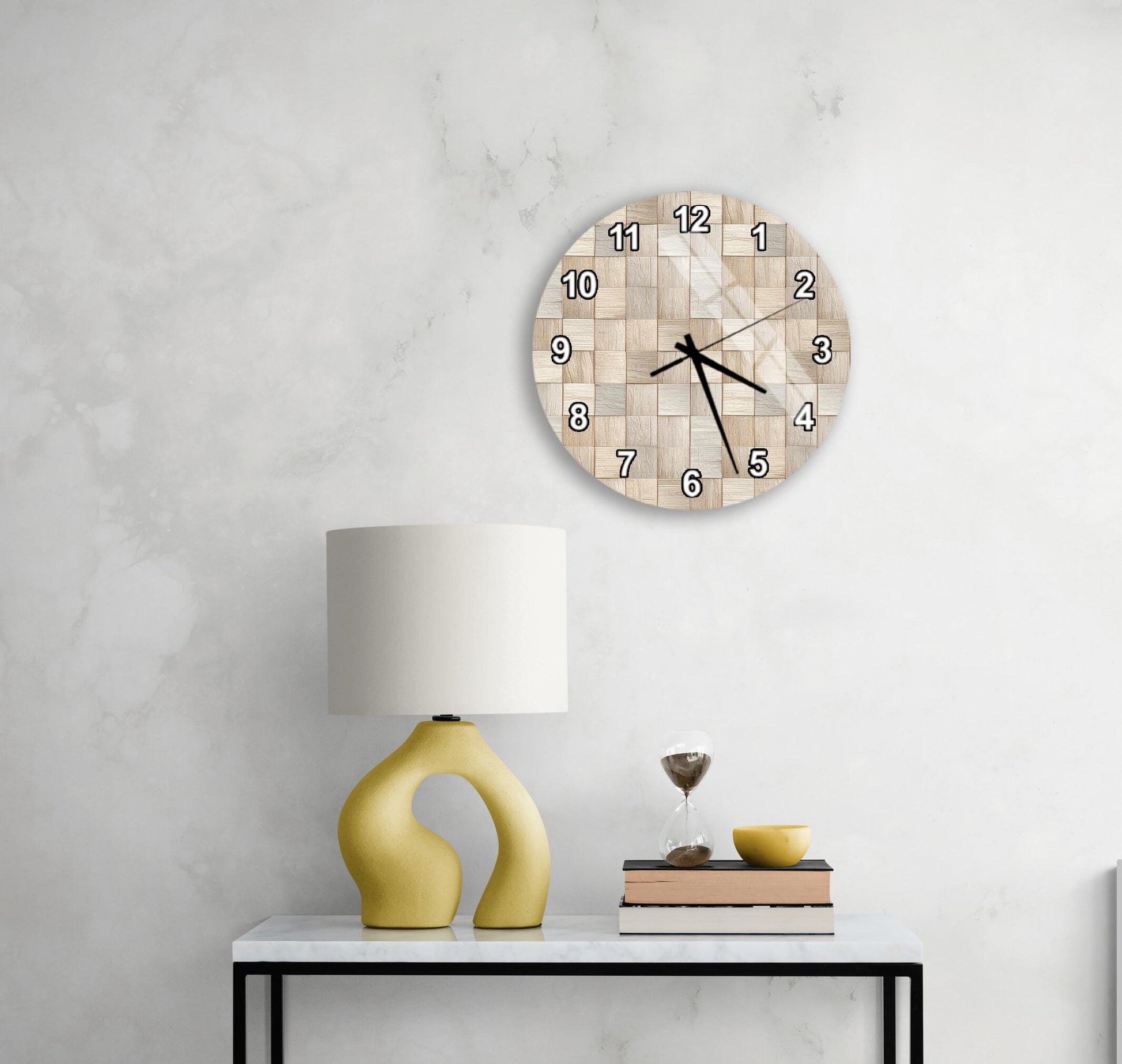 a modern living room with a white marble wall, a round clock with a wooden frame, a yellow lamp with a unique curved base, and a small table with a stack of books and a glass of wine.