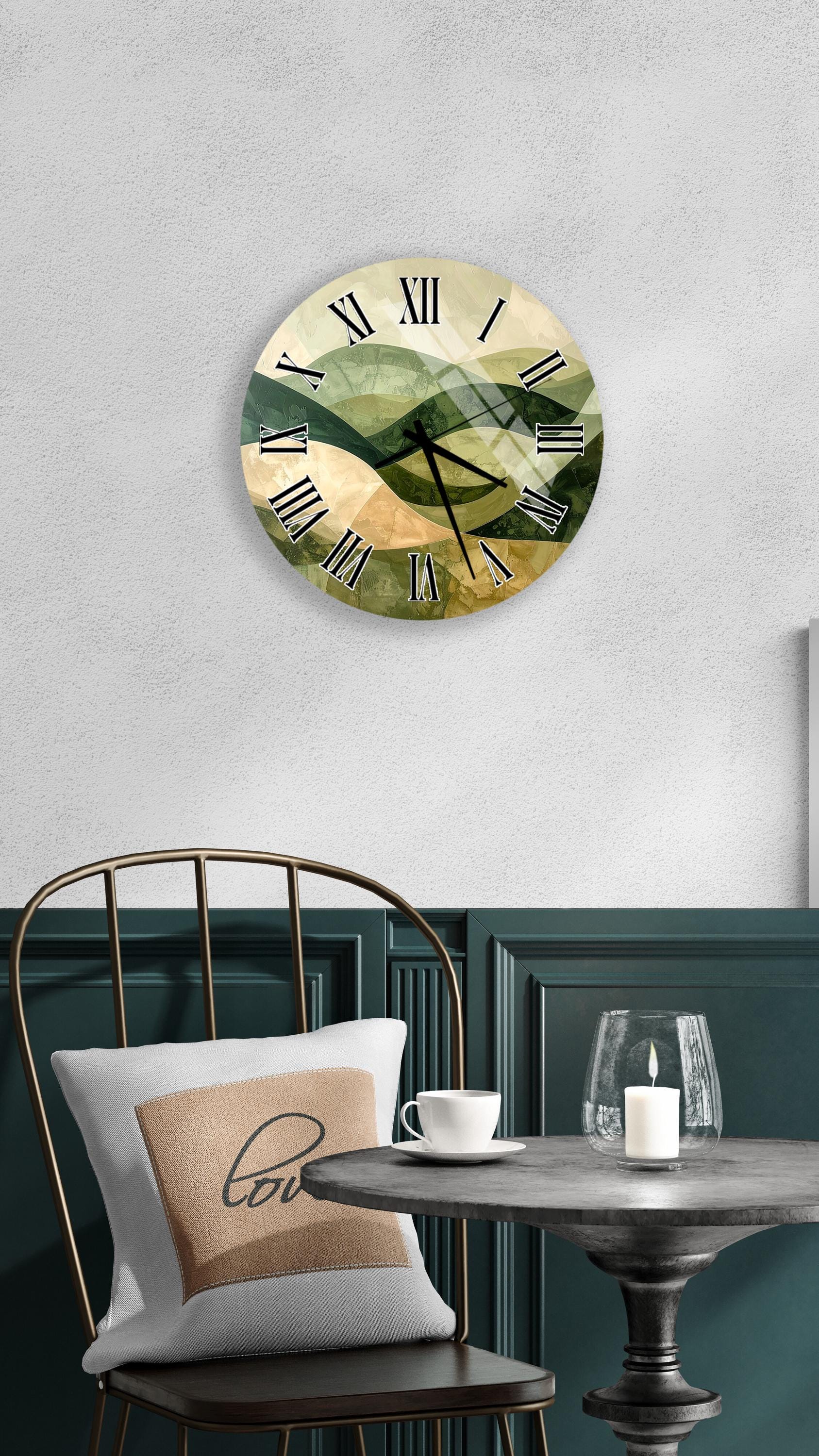 a wall clock with a green and gold design, mounted on a wall above a table with a white tablecloth. The table has a white cup and a candle on it, creating a cozy and inviting atmosphere.