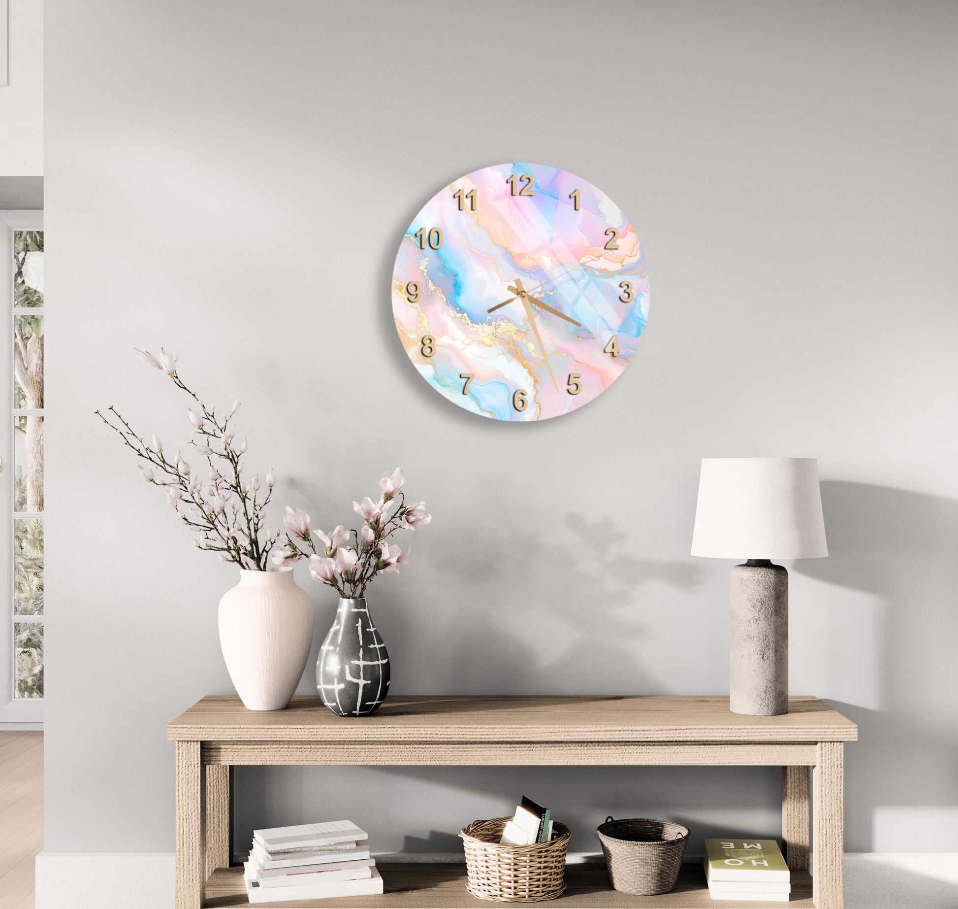 a wall clock with a marble-like design, a wooden table with a lamp, a vase with flowers, and some books on a shelf.
