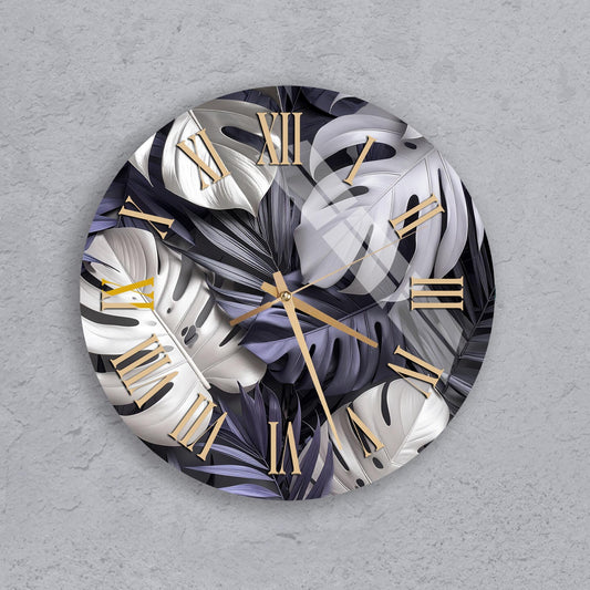 A round wall clock with a design featuring a combination of white and black leaves, along with gold Roman numerals.