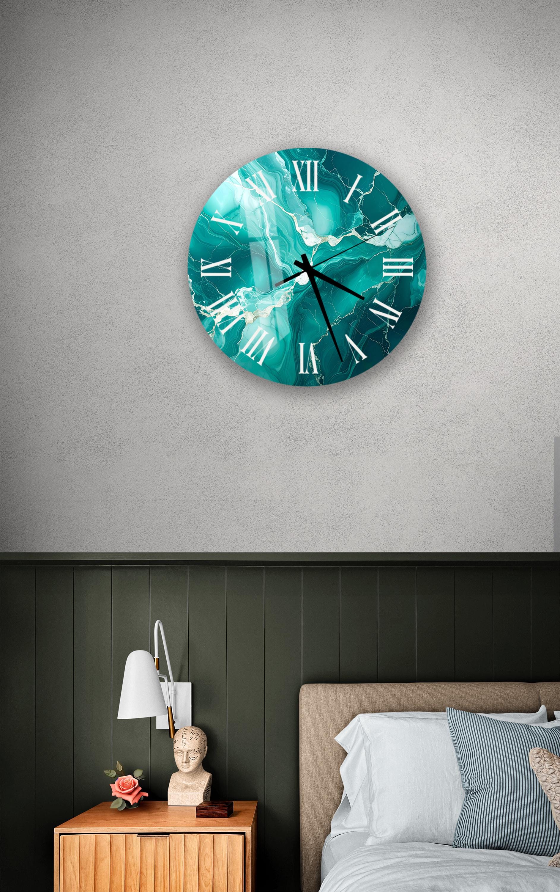 a bedroom setting with a large wall clock displaying a turquoise marble design. The clock is mounted above a bed with a white headboard. The room has a green wall and a wooden nightstand with a lamp and a vase of flowers.