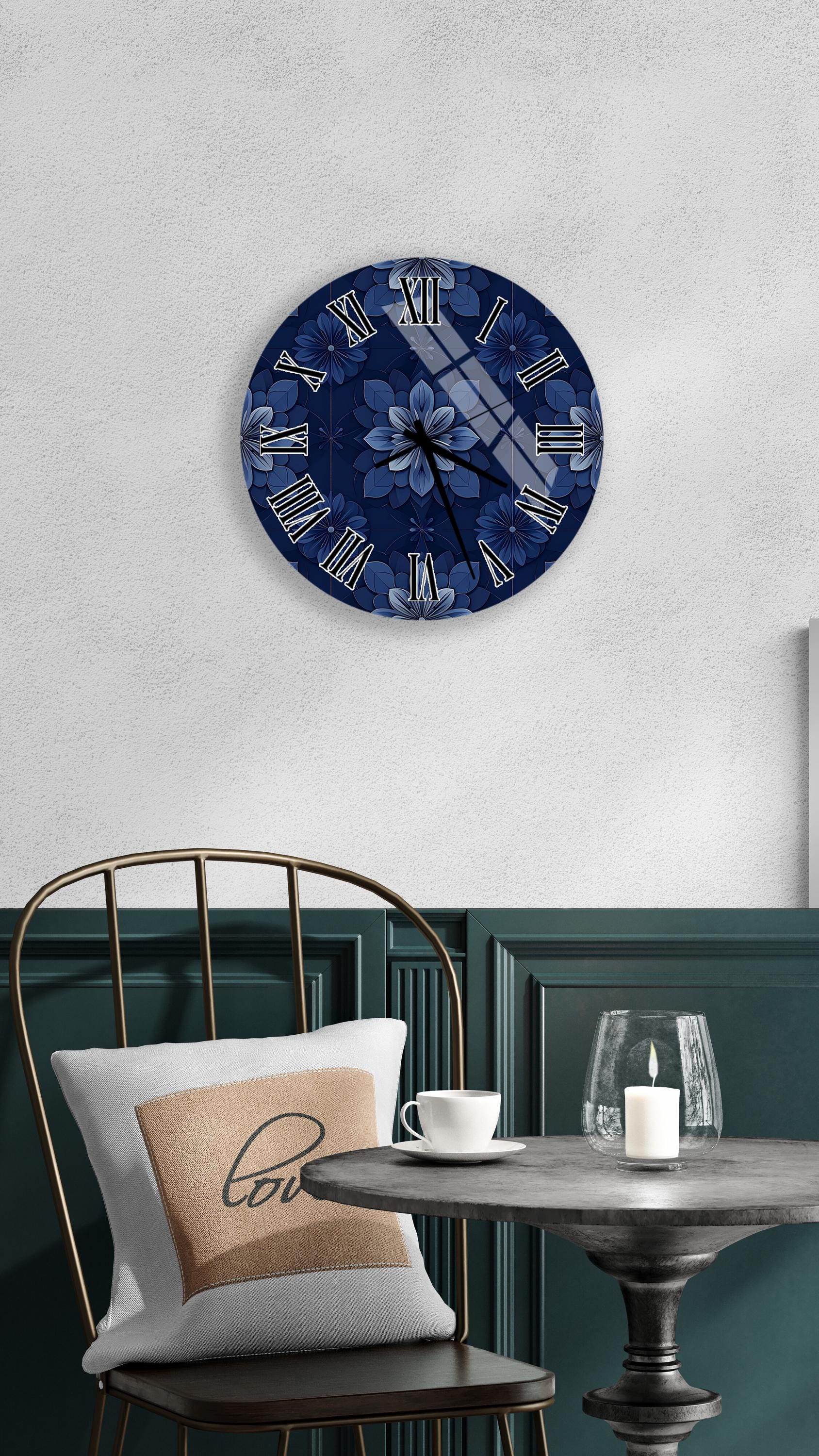 a round wall clock with a blue floral design, mounted on a white wall above a dining table with a white tablecloth. The table is set with a white cup and a candle, creating a cozy and inviting atmosphere.