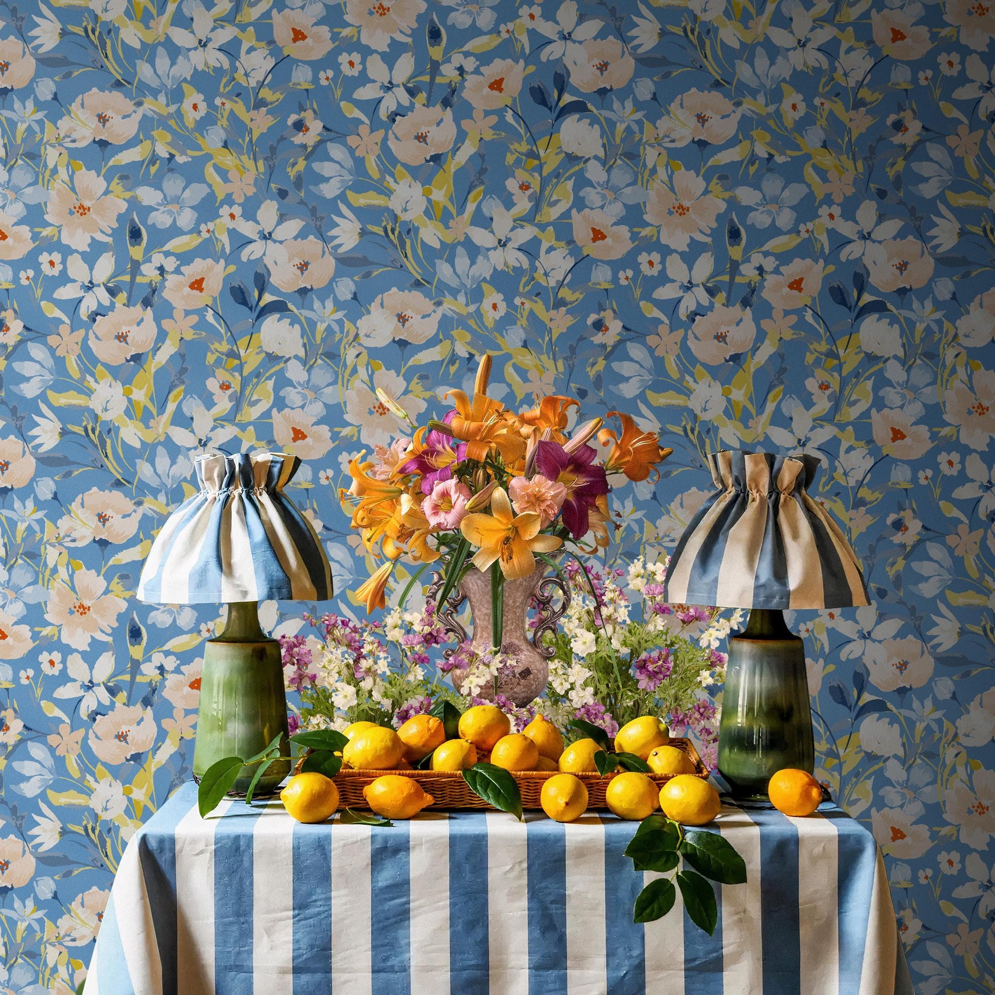 a table with a blue and white striped tablecloth, a vase of flowers, and a basket of lemons. The table is set against a blue floral wallpaper.