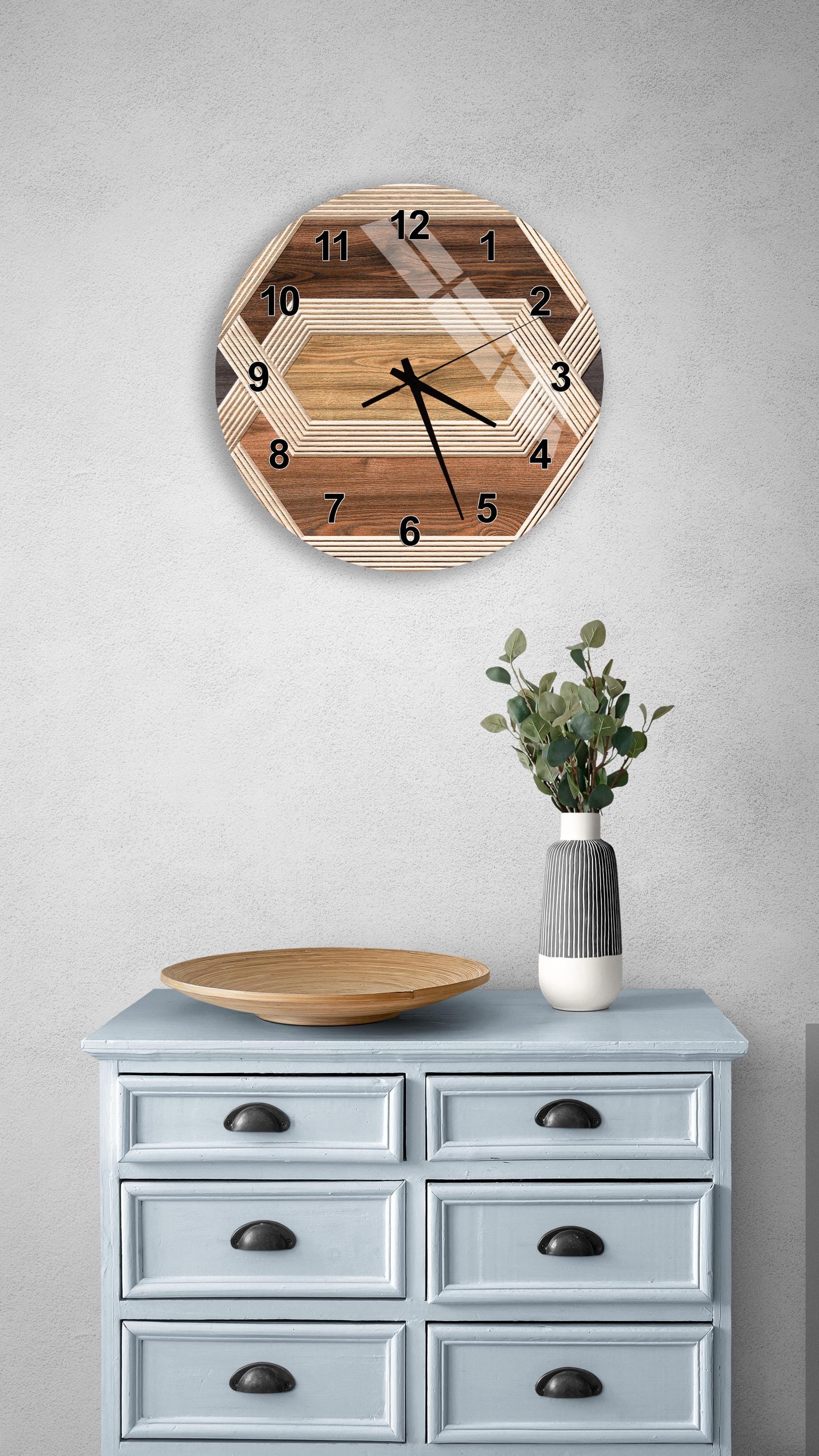 a wooden clock with a geometric design, mounted on a wall above a light blue dresser with six drawers. The dresser also has a vase with greenery on it, and a wooden plate on top.