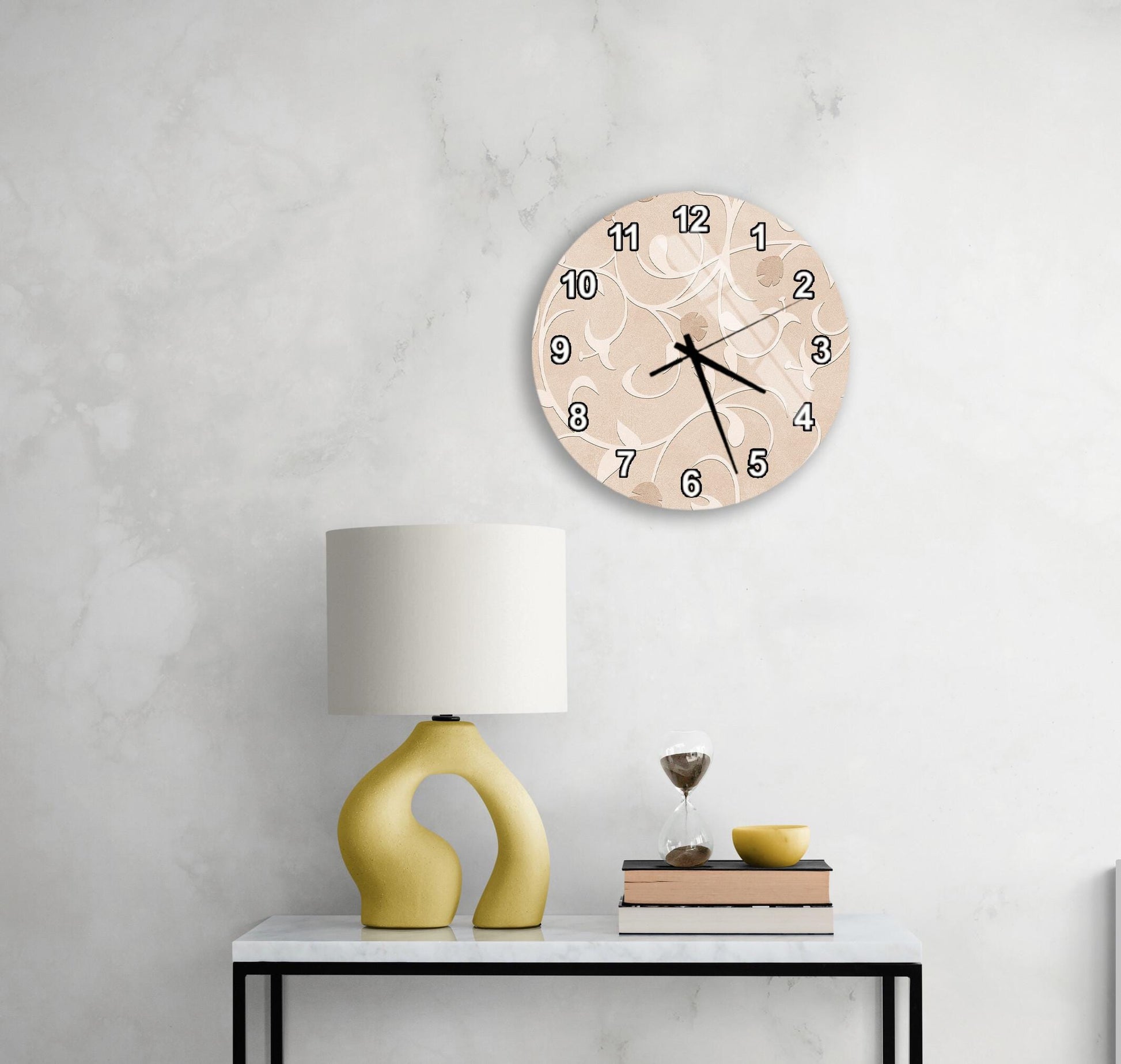 a modern living room with a white marble wall, a round clock with a beige and white design, a yellow lamp with a unique curved base, and a small table with a book and a glass of wine.
