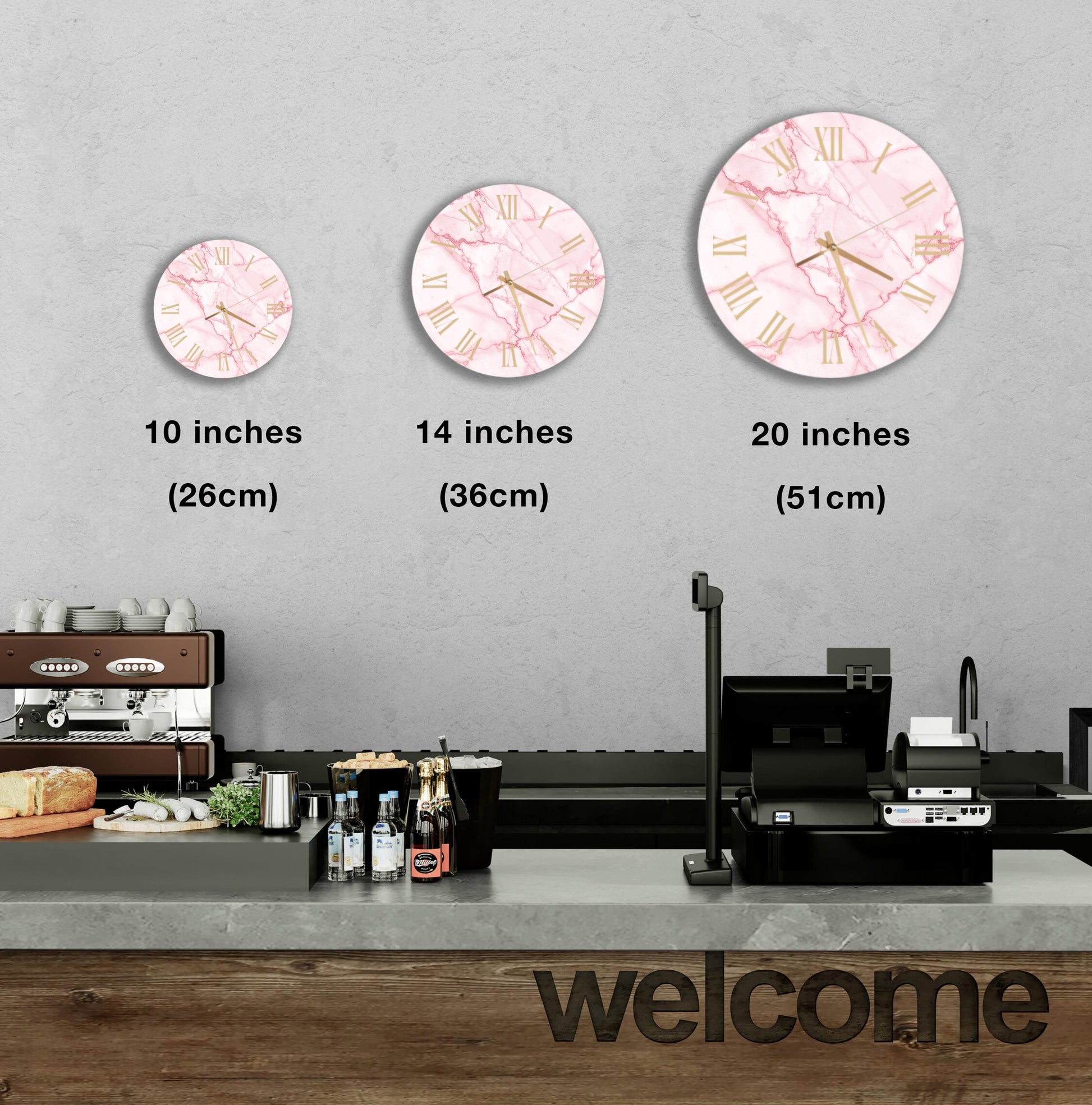 A wall clock is displayed on a wall, with three different sizes of the same clock. Below the wall clock, there is a counter with various items on it, and a "welcome" sign is visible.