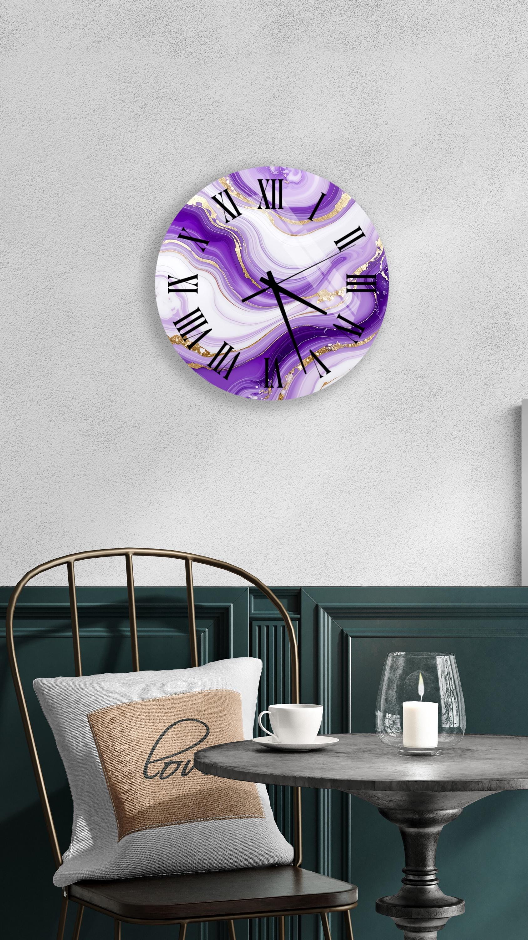 a round wall clock with a purple marble design, mounted on a wall above a dining table with a white tablecloth. The table is set with a white cup and a candle, creating a cozy and inviting atmosphere.