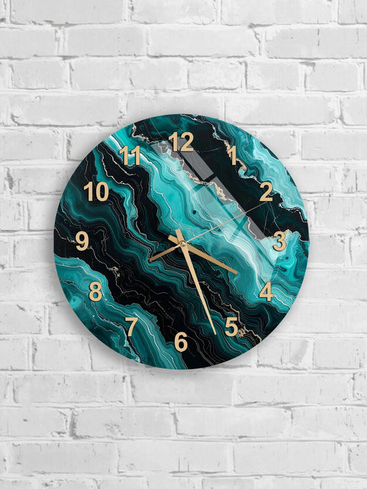 A wall clock with a marble-like design in shades of blue and black, mounted on a white brick wall.