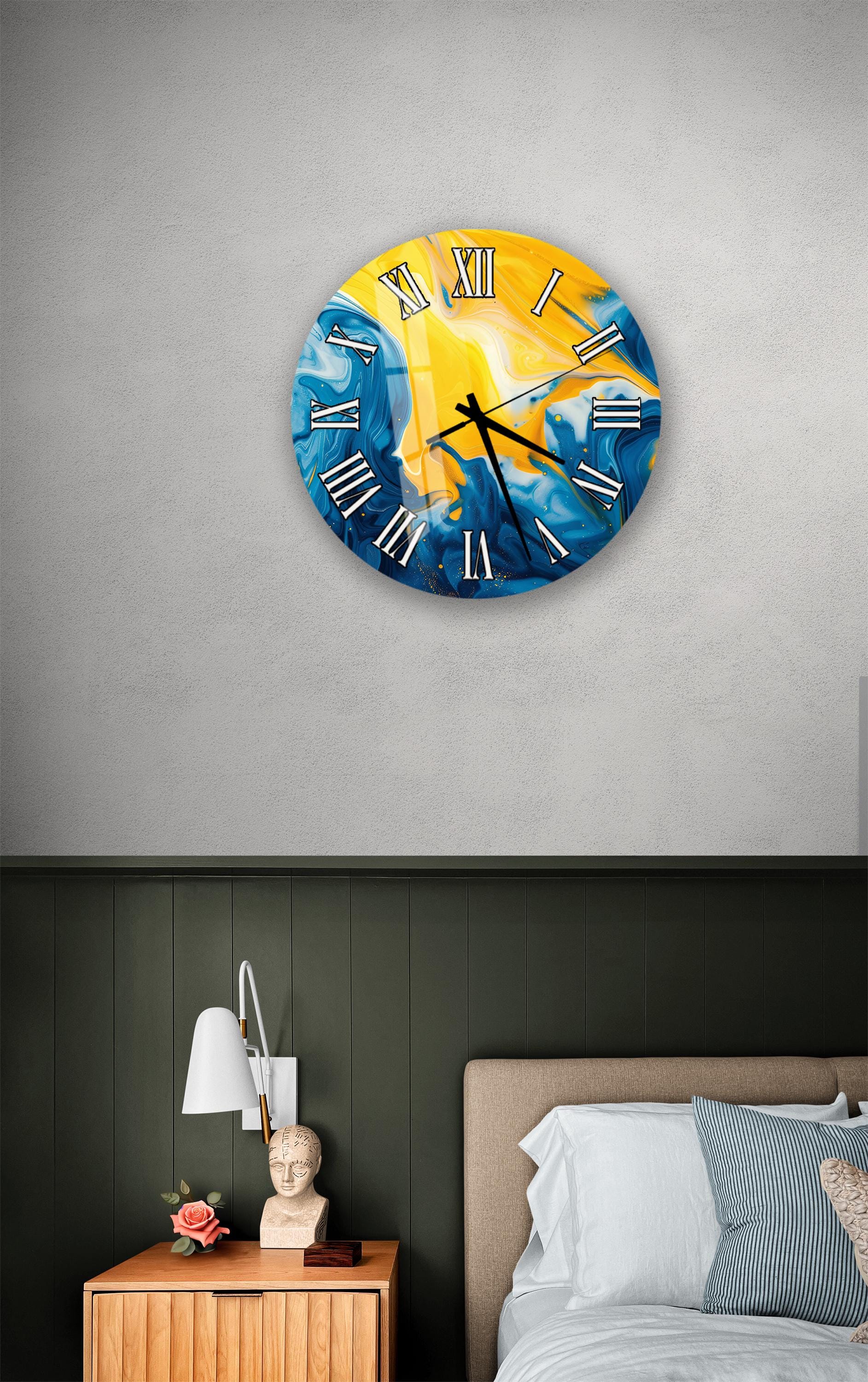 a bedroom setting with a wall clock displaying a vibrant blue and yellow design, a wooden nightstand with a lamp, and a bed with white sheets and pillows.