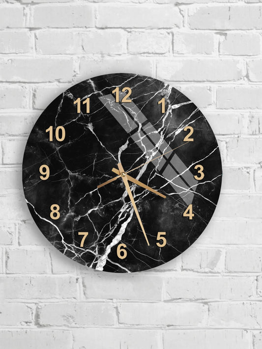 A black and white marble wall clock with gold hands and numbers is mounted on a white brick wall.