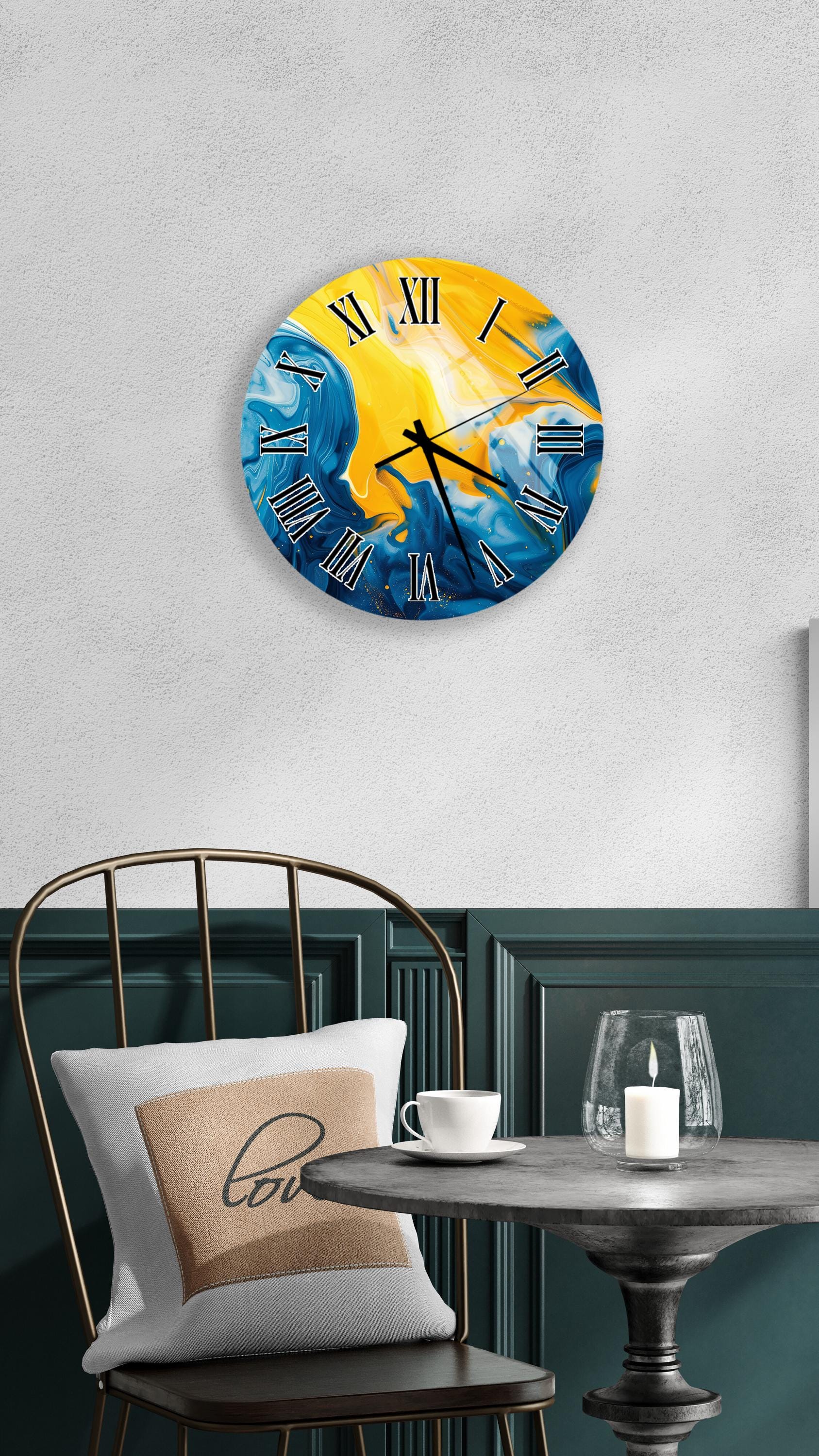 a wall clock with a vibrant blue and yellow design, hanging on a wall above a table with a white tablecloth. The table is set with a white cup and a candle, creating a cozy and inviting atmosphere.