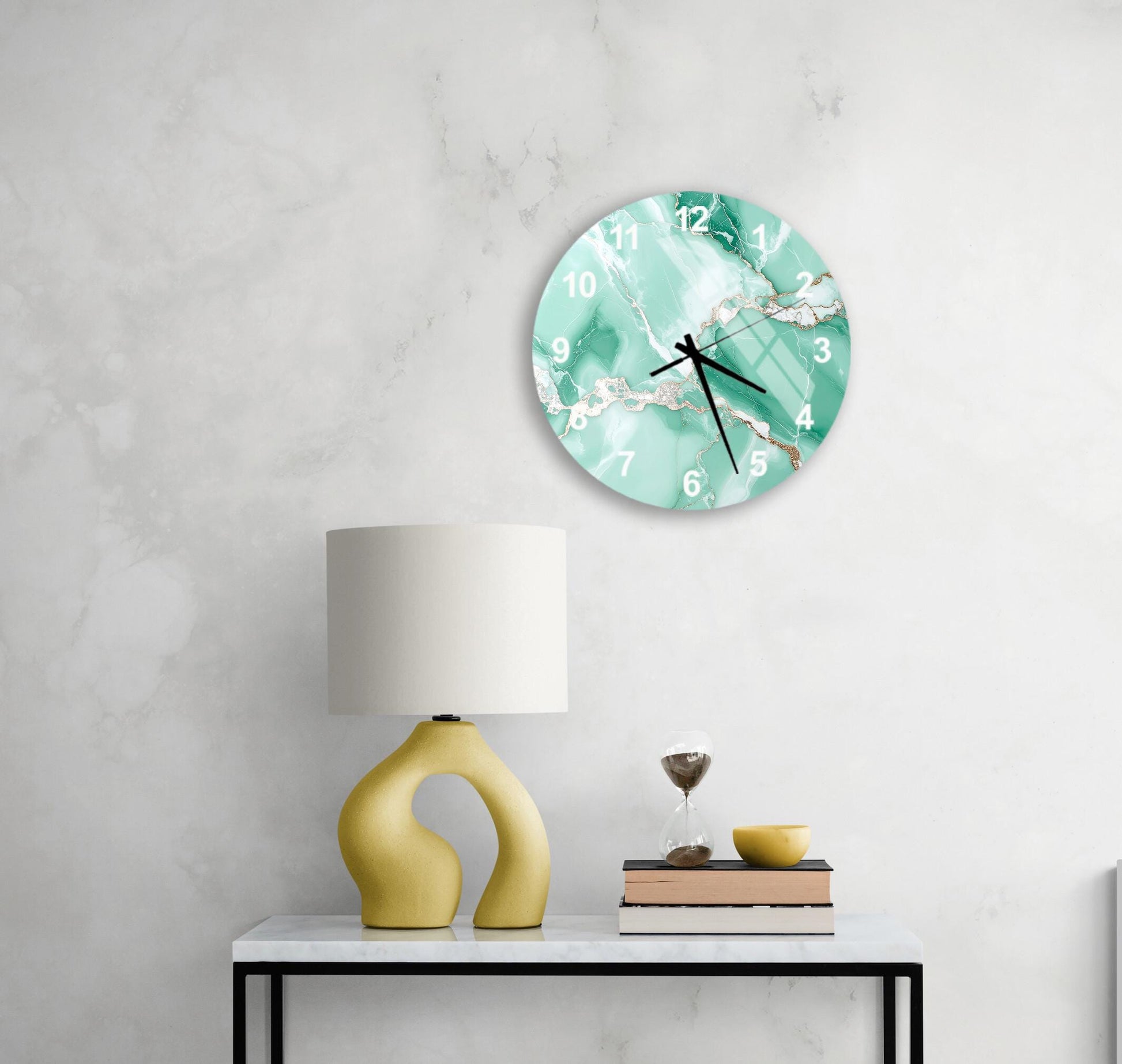 a modern, minimalist living space with a white marble wall, a round clock with a marble design, a yellow lamp with a unique, curved base, and a small table with a book and a glass of wine.