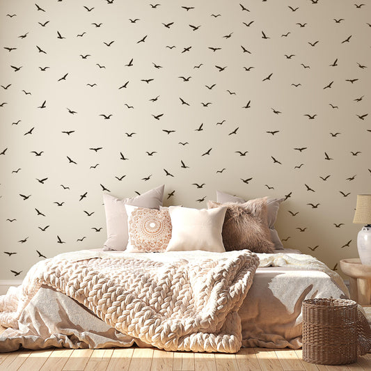 a bedroom with a bed covered in a white comforter and pillows, and a wall with a repeating pattern of black birds.