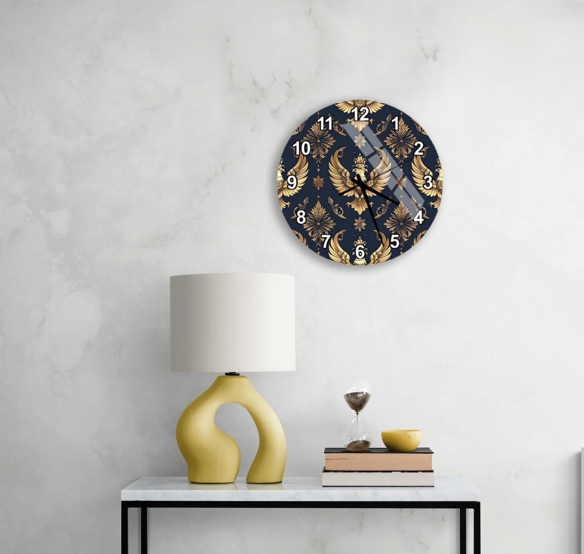a stylish clock with a gold and navy blue design, mounted on a wall above a white table with a yellow lamp and a stack of books.