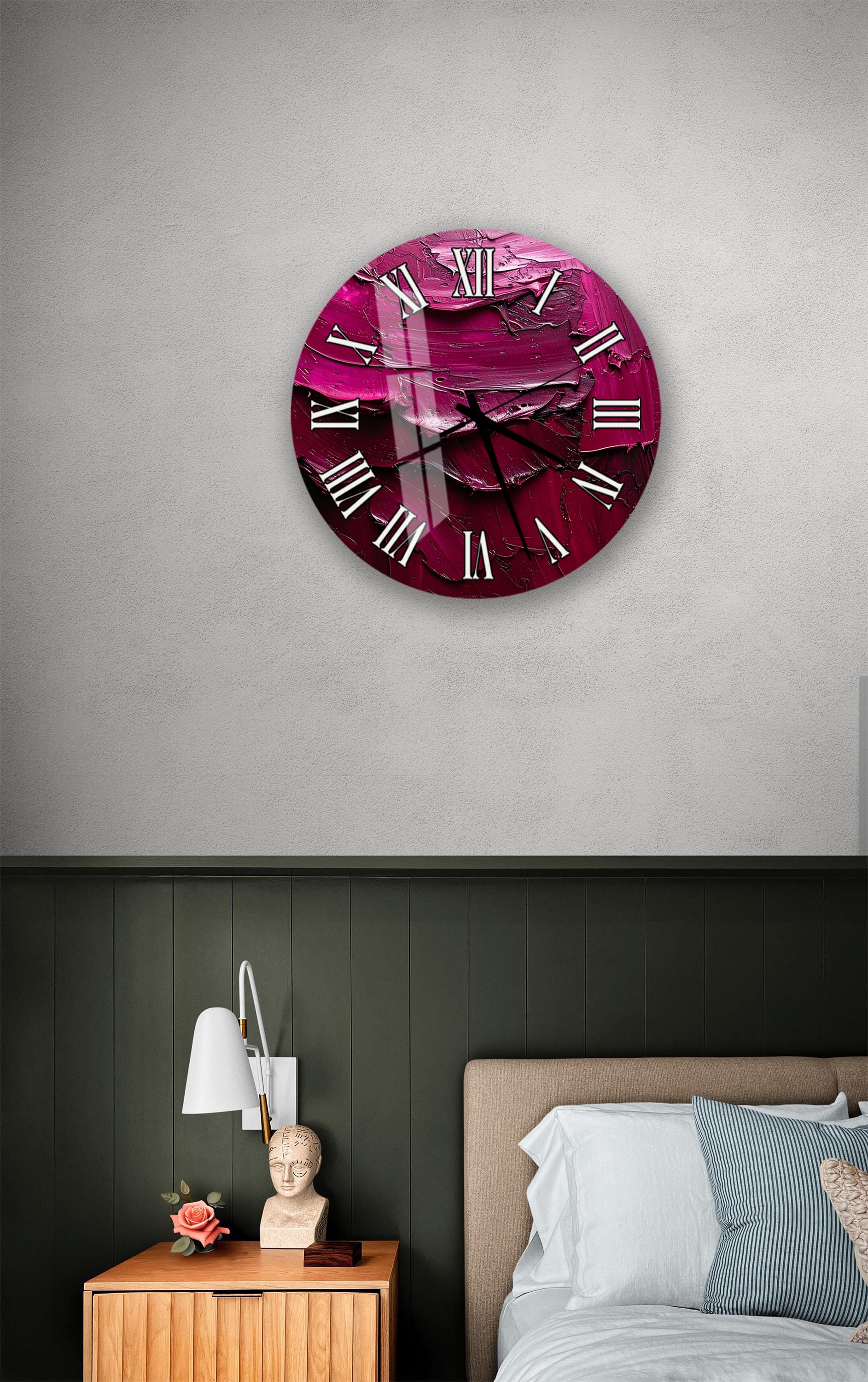 a large, round clock with a pink and purple color scheme, mounted on a wall above a bed with a wooden headboard.