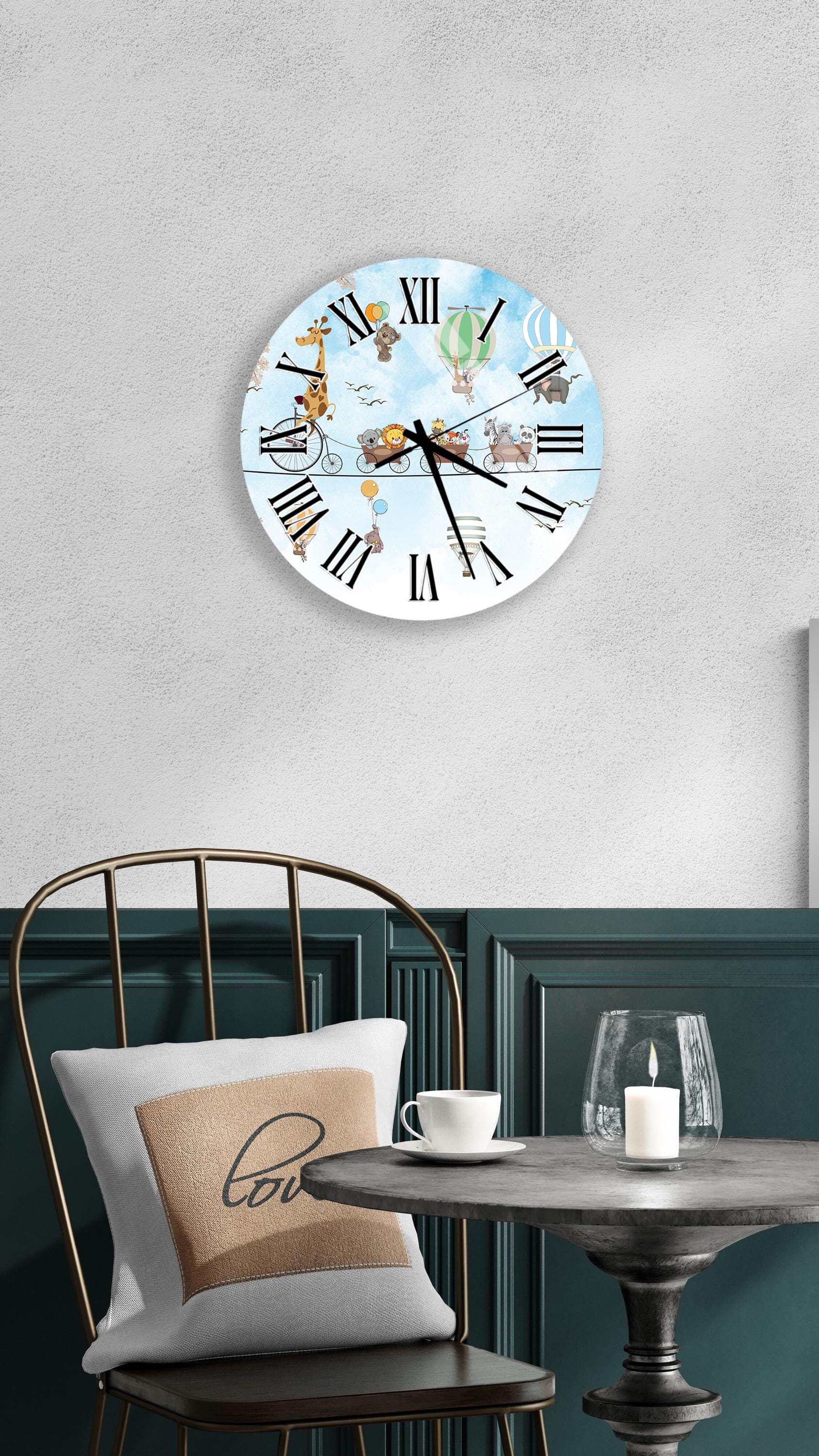 a wall clock with a whimsical design, depicting animals and objects in a playful manner. The clock is mounted on a wall above a table with a white tablecloth and a candle on it. A chair with a pillow on it is positioned in front of the table.