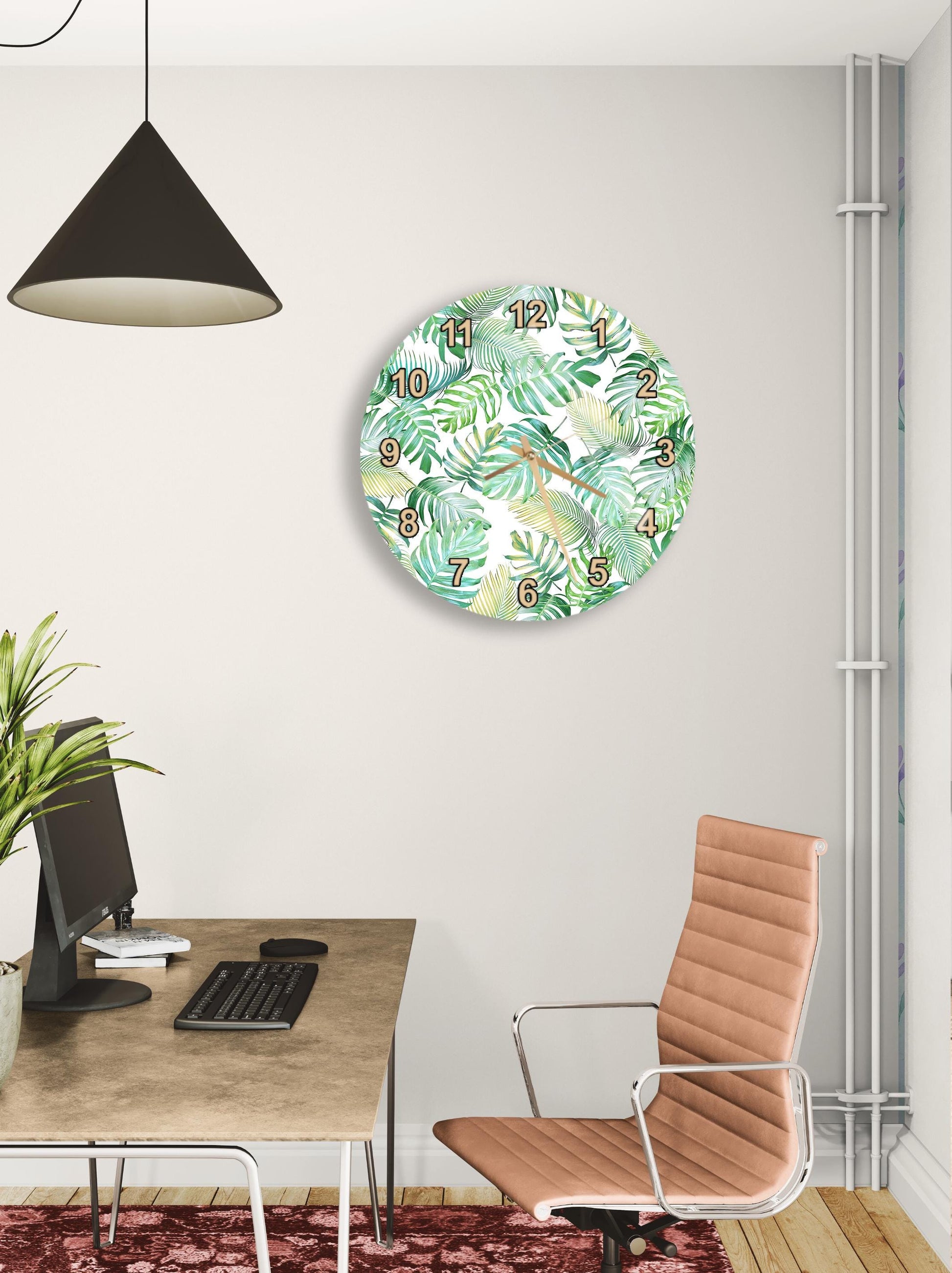 a modern office space with a round clock displaying a tropical leaf pattern, a wooden desk with a computer setup, and a brown leather office chair.
