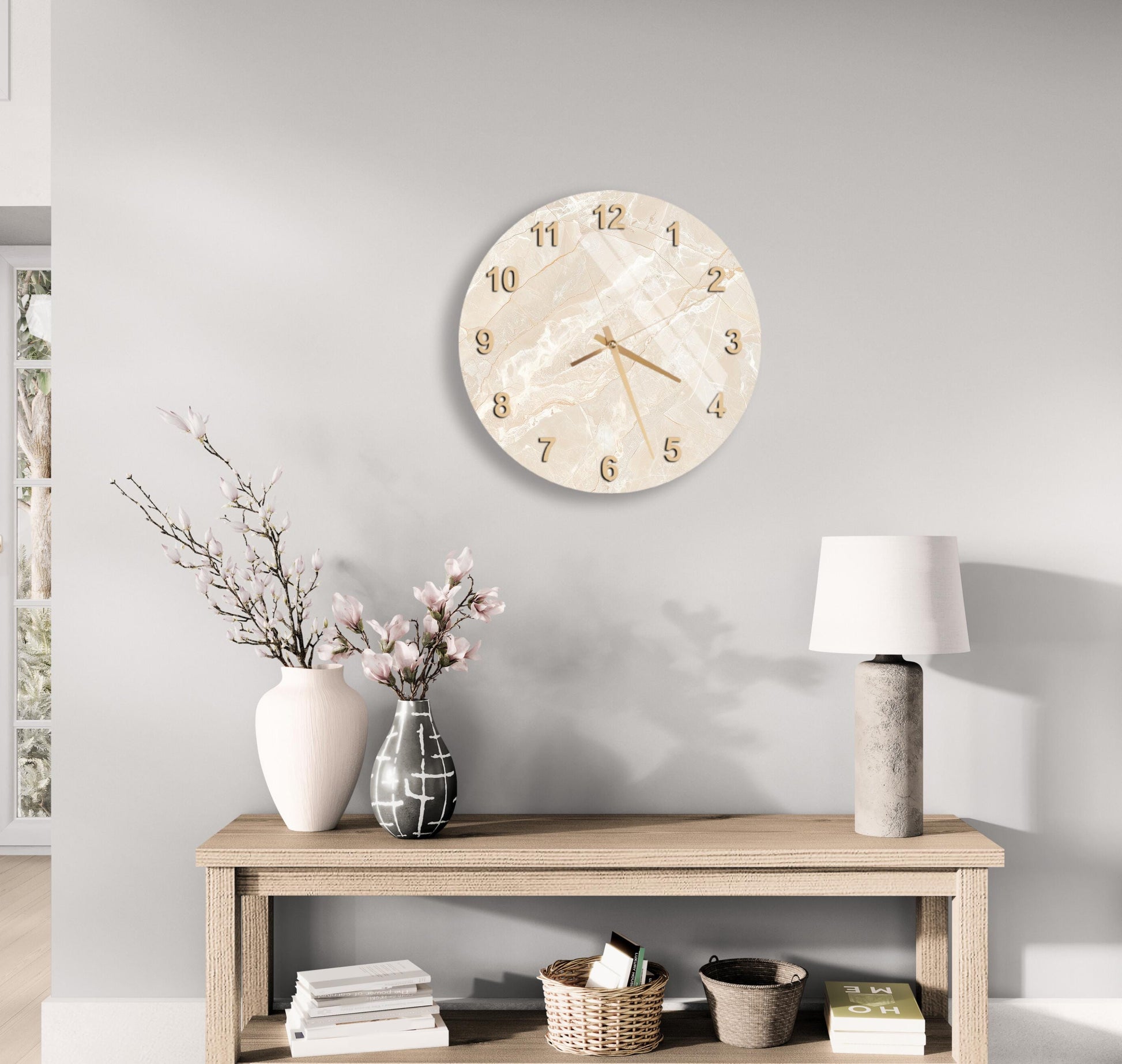a minimalist living room with a round wall clock, a wooden table with a lamp, a vase with flowers, and a stack of books.