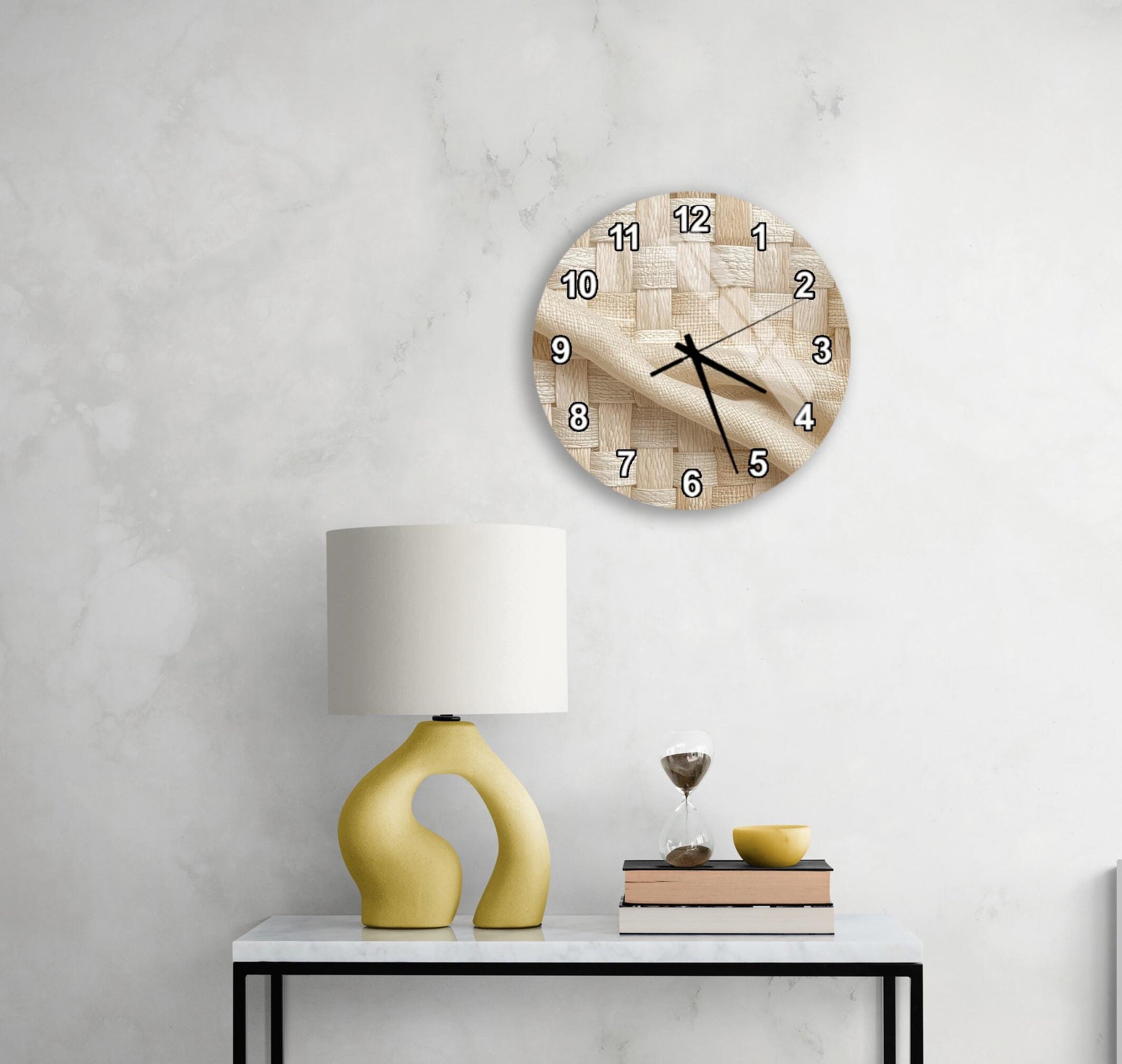 a modern living room with a white marble wall, a round wooden clock with a unique design, a yellow lamp with a curved base, a stack of books, and a glass of wine on a white table.
