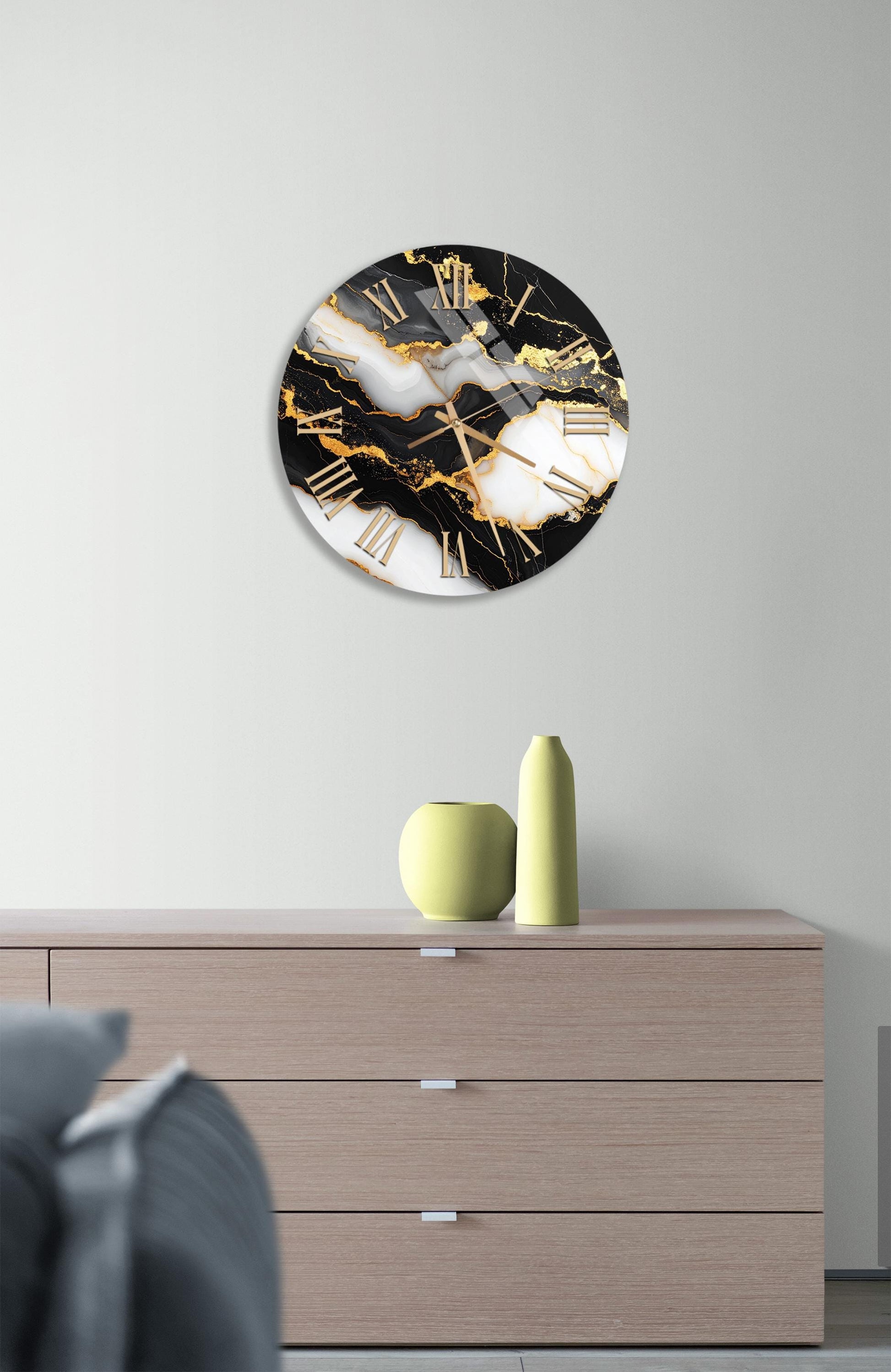 a modern clock with a black and white marble design, mounted on a wall above a wooden dresser.