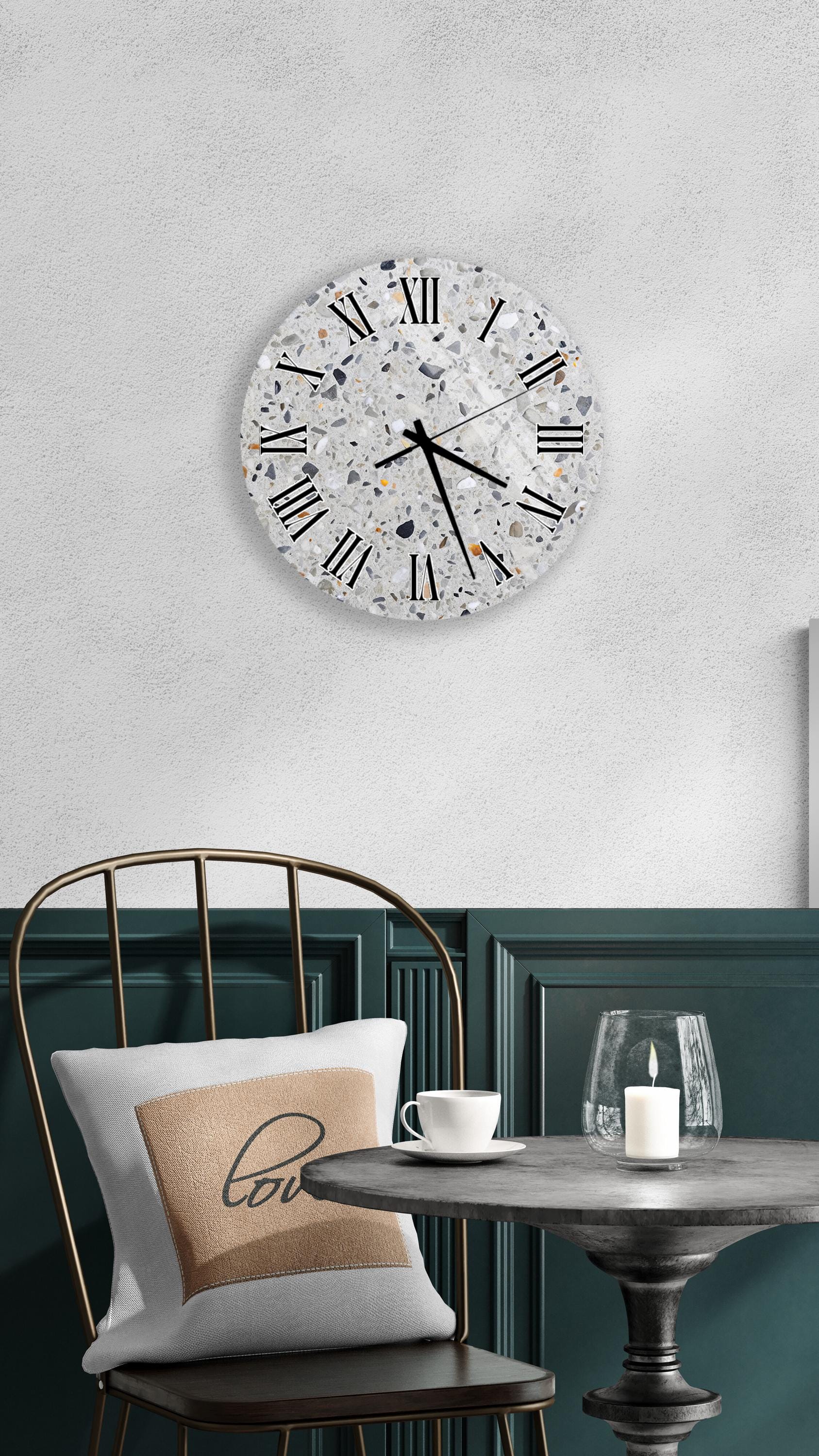 a modern interior design with a large round wall clock, a white table with a candle, and a black metal chair.