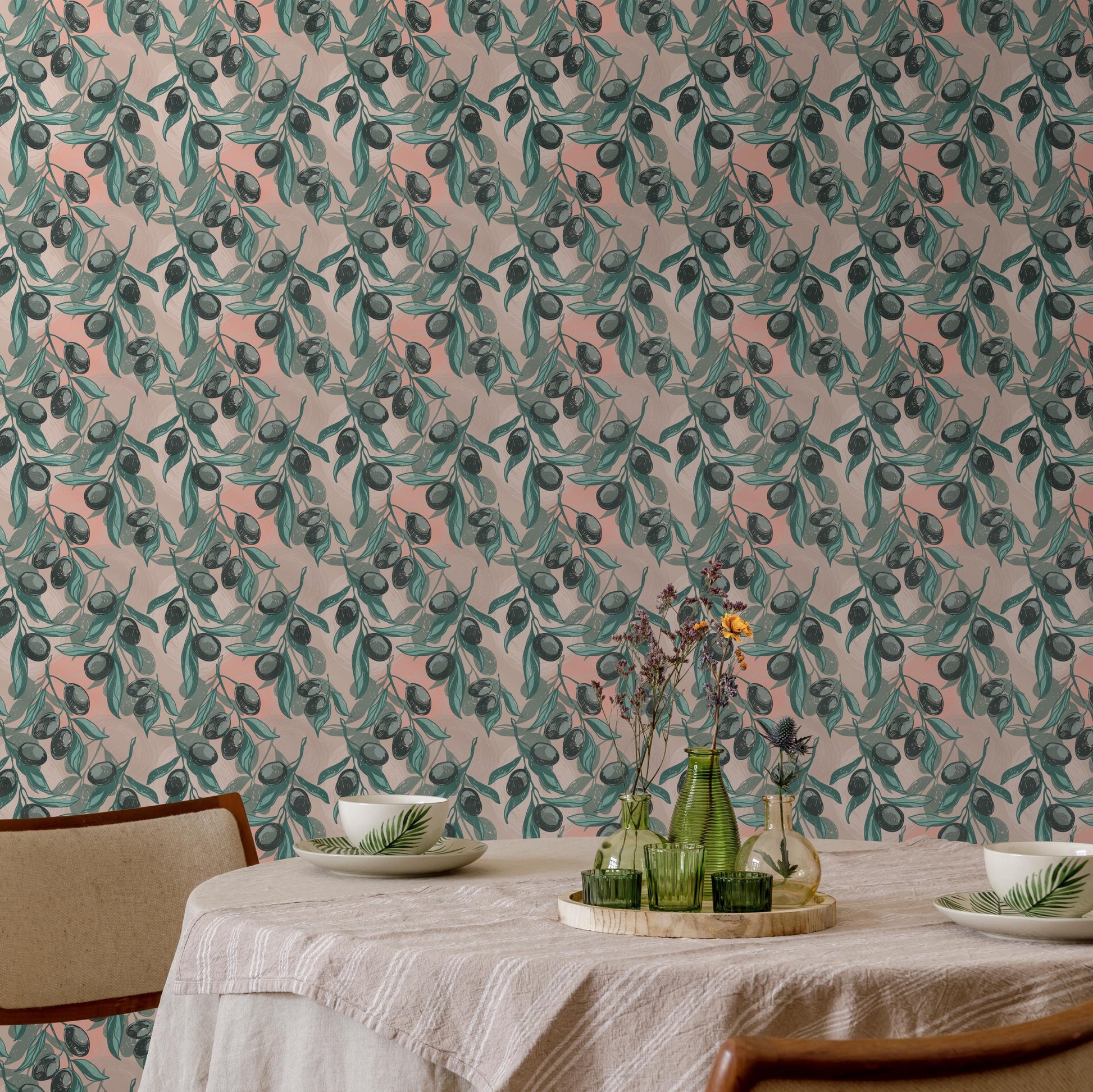a dining table set with a white tablecloth, two white plates, and two green vases with flowers. The table is positioned against a wall with a repeating pattern of green leaves and flowers, creating a harmonious and visually appealing setting.