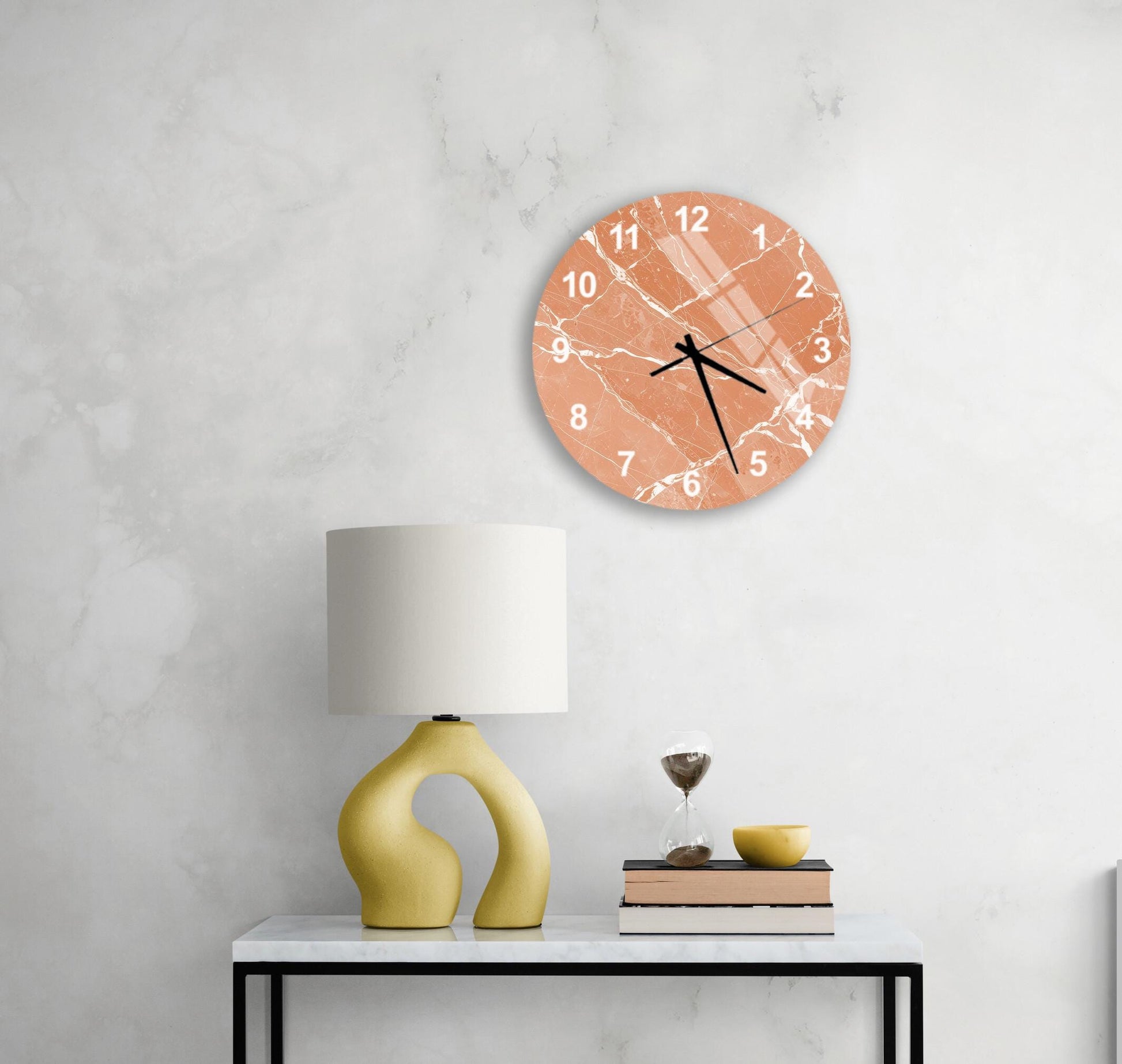 a modern living room with a white marble wall, a round orange wall clock, a yellow lamp, a white table, and a stack of books.