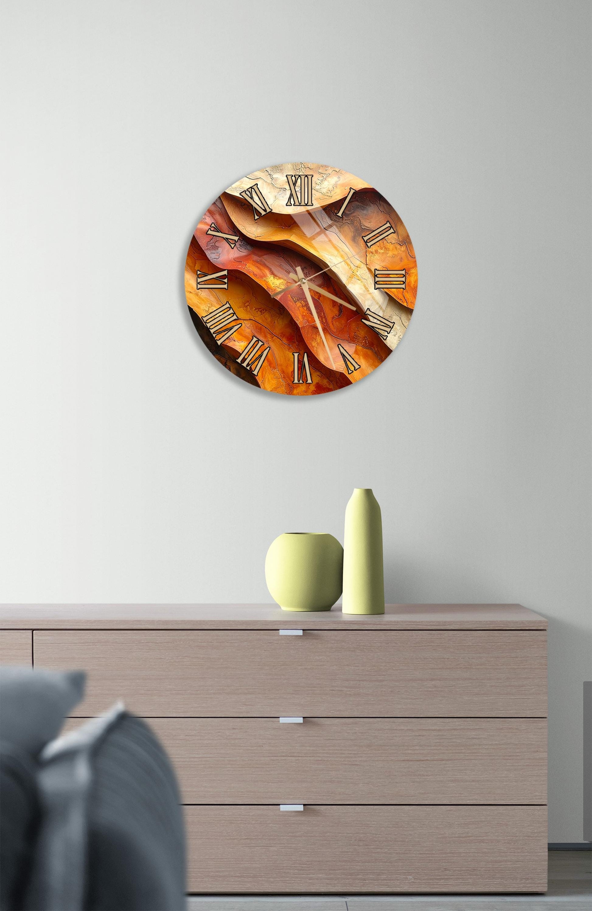 a modern clock with a unique design, hanging on a wall above a wooden dresser.
