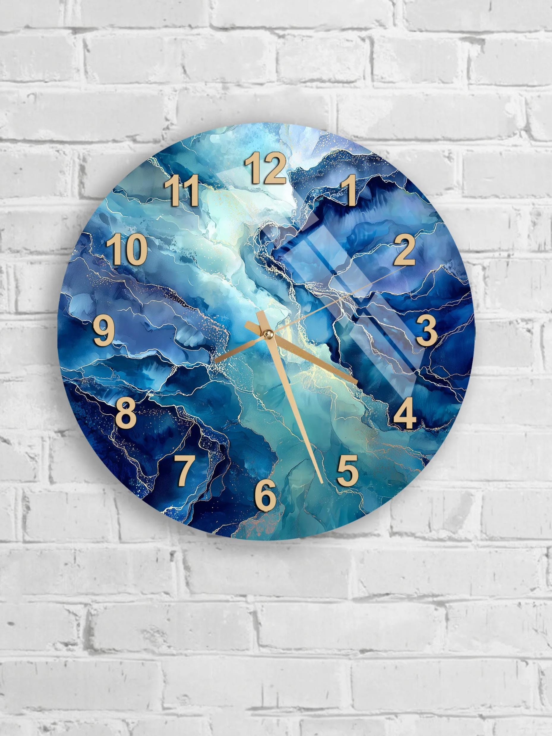 A wall clock with a blue marble-like design and gold numbers is mounted on a white brick wall.