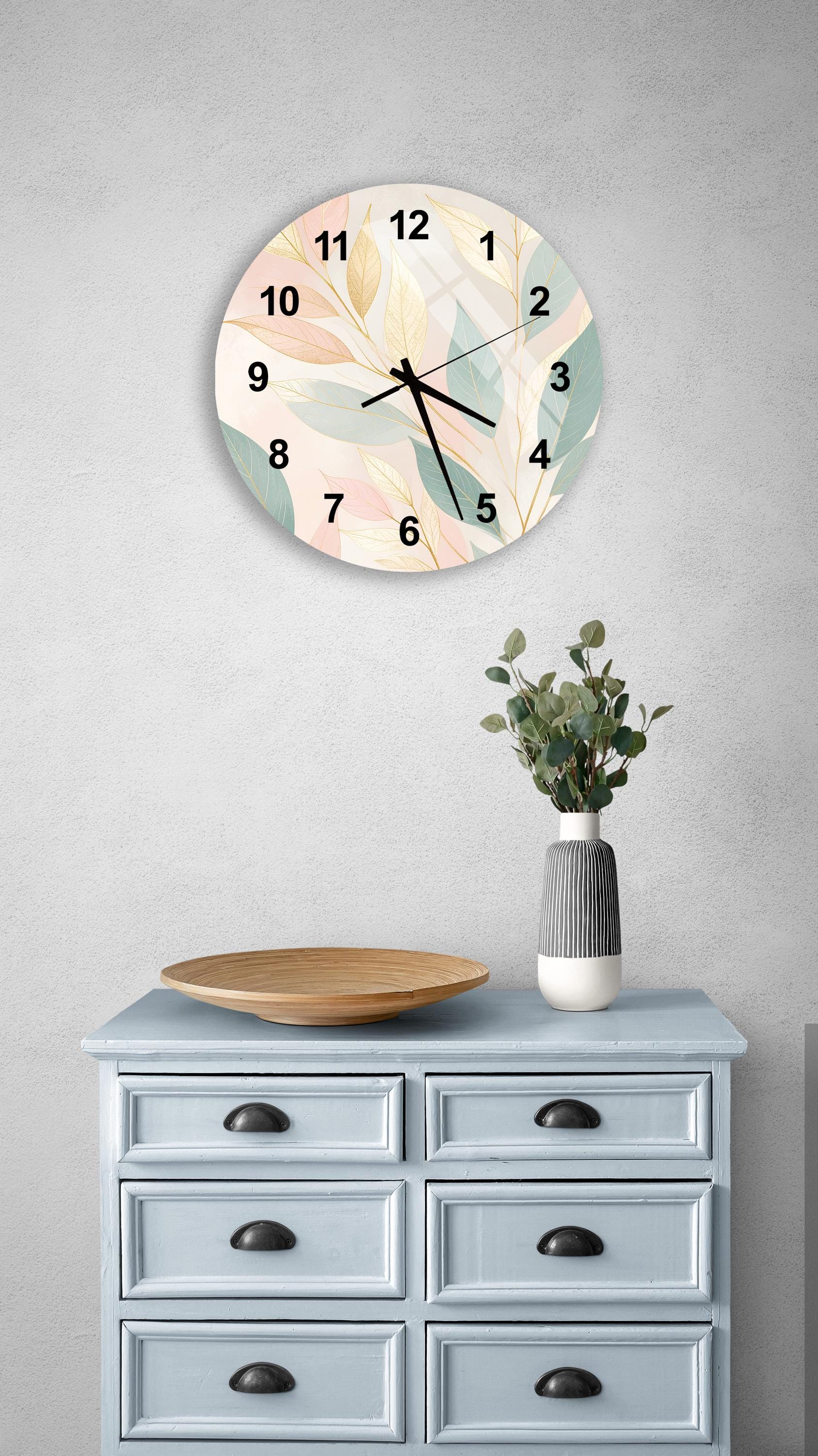 a wall clock with a floral design, a wooden tray, a vase with greenery, and a light blue dresser with six drawers.