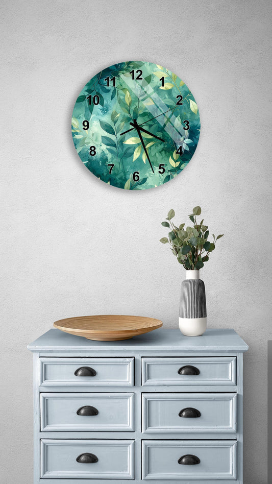 a wall clock with a green leaf design, a wooden bowl on a light blue dresser, and a vase with greenery on a gray wall.