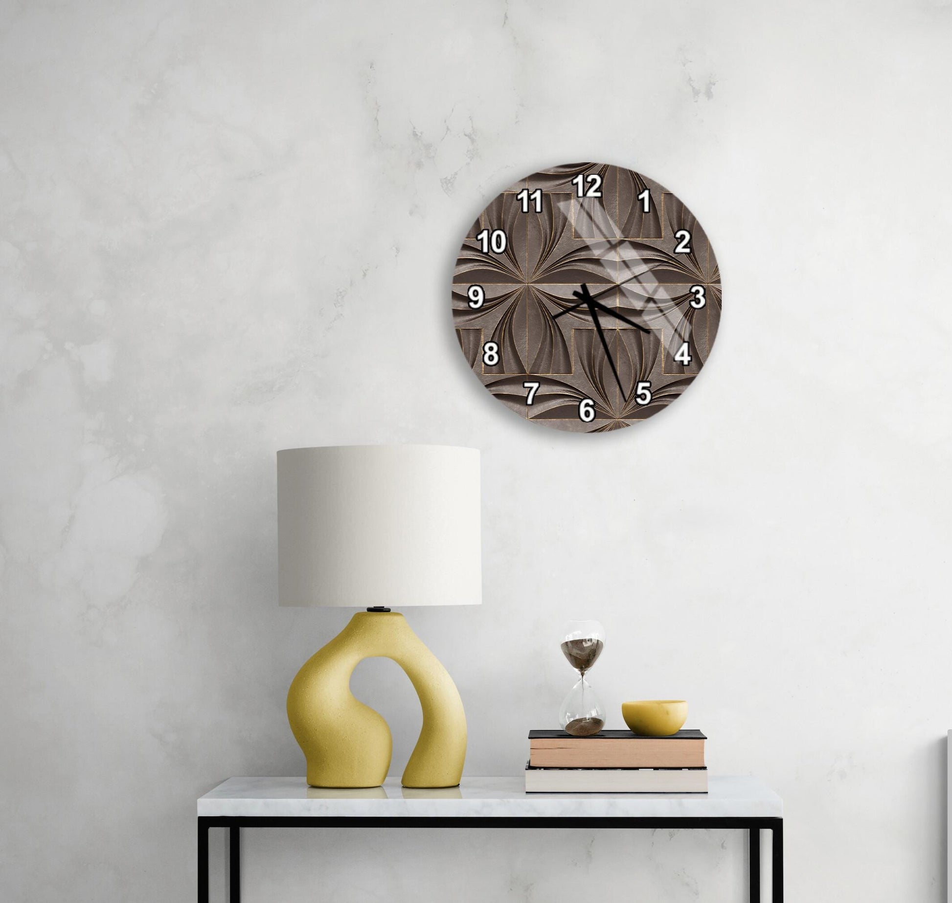 a modern living room with a white marble wall, a round clock with a brown floral design, a yellow lamp with a unique curved base, a stack of books, and a glass of wine on a white table.