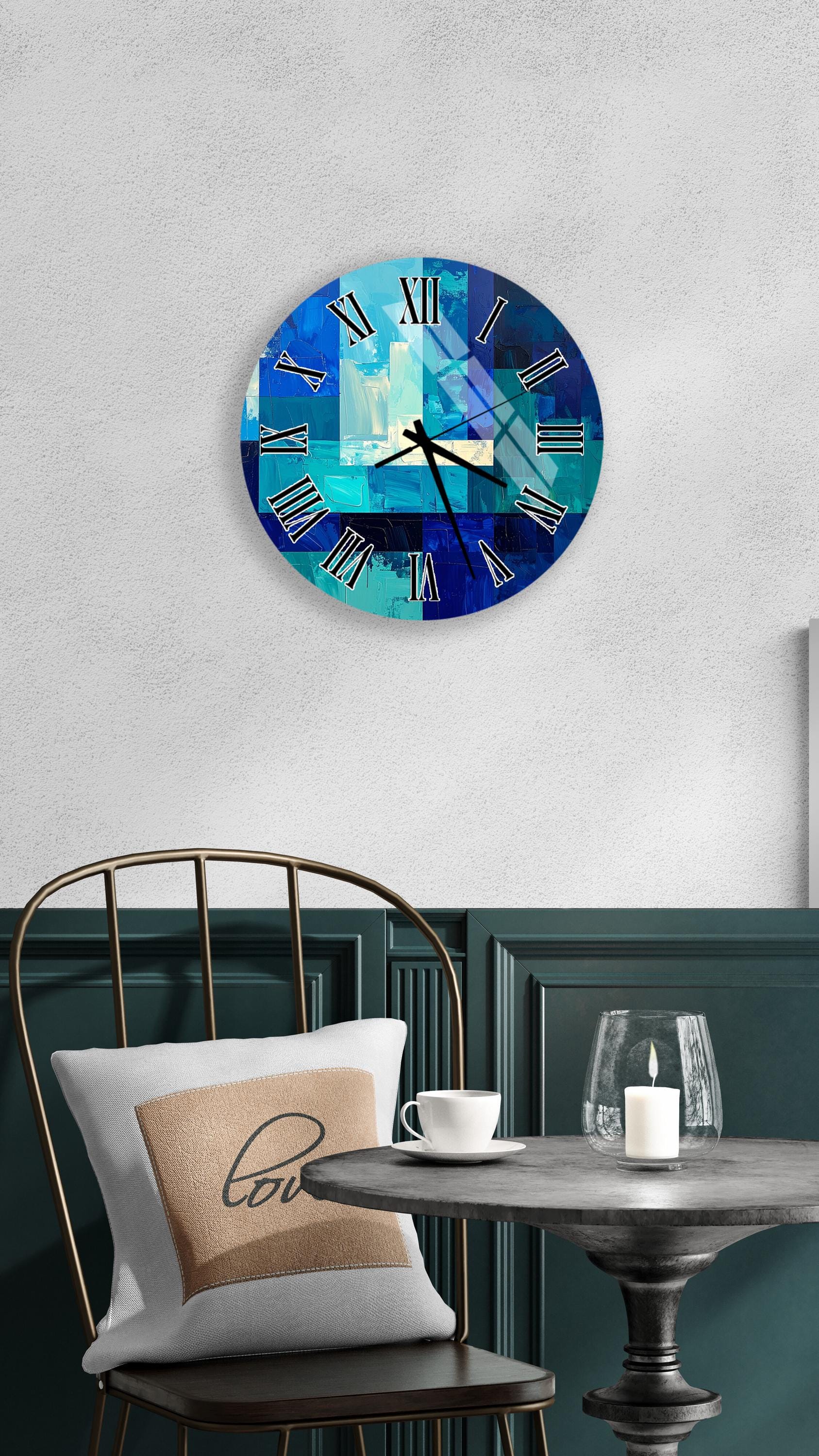 a modern, abstract clock with a blue and white color scheme, mounted on a wall above a table with a white tablecloth. The table is set with a white cup and a candle, creating a cozy and inviting atmosphere.