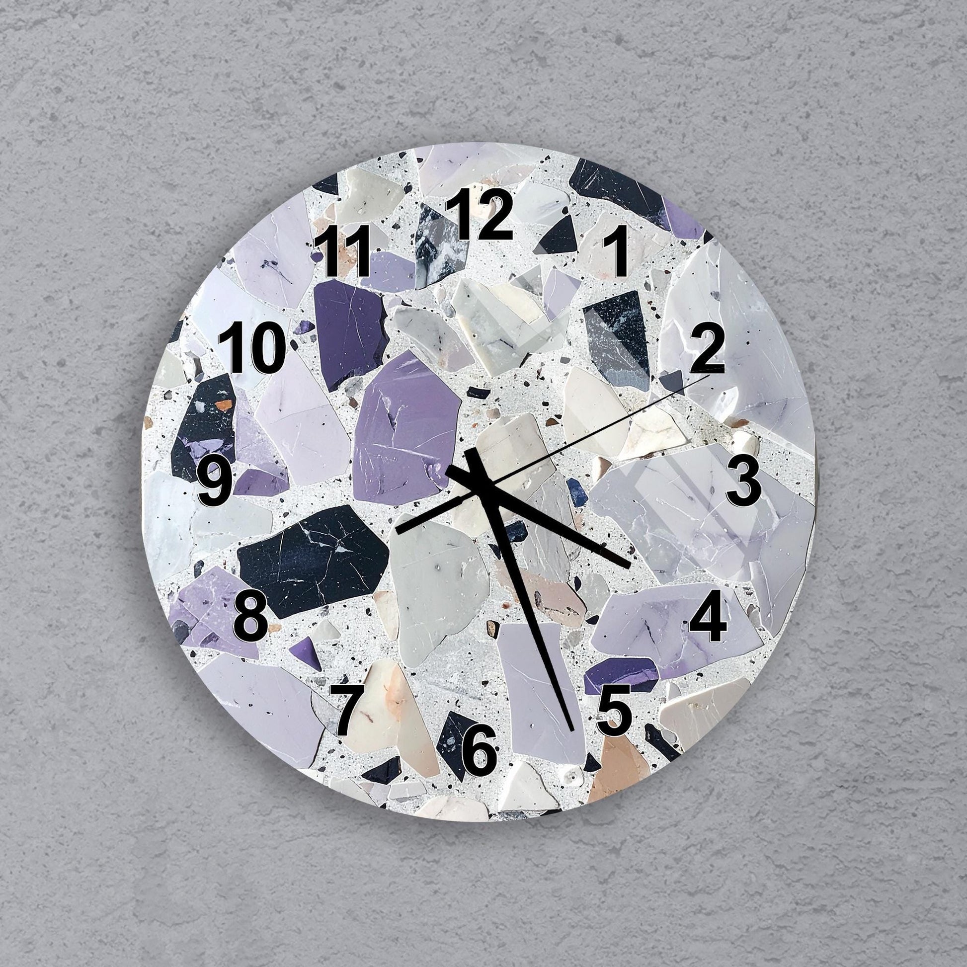 A wall clock with a mosaic design featuring various shades of purple, white, and gray.