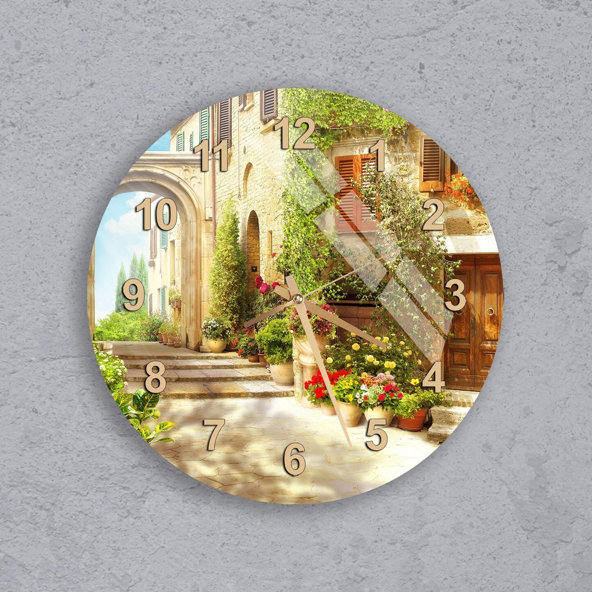 A wall clock with a scenic outdoor view of a building, plants, and steps.